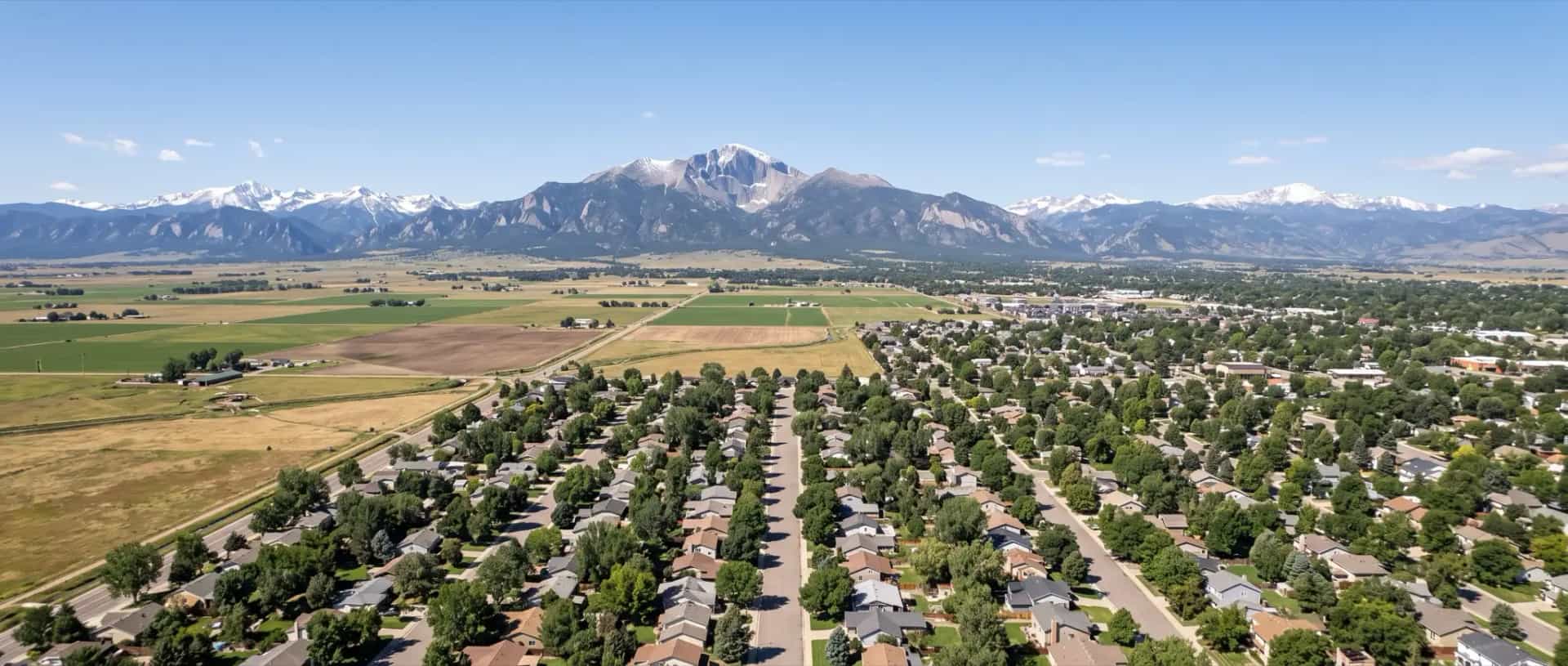 Illustrative representation of rooftops giving way to farmland near Longmont, Colorado with Longs Peak on the western horizon