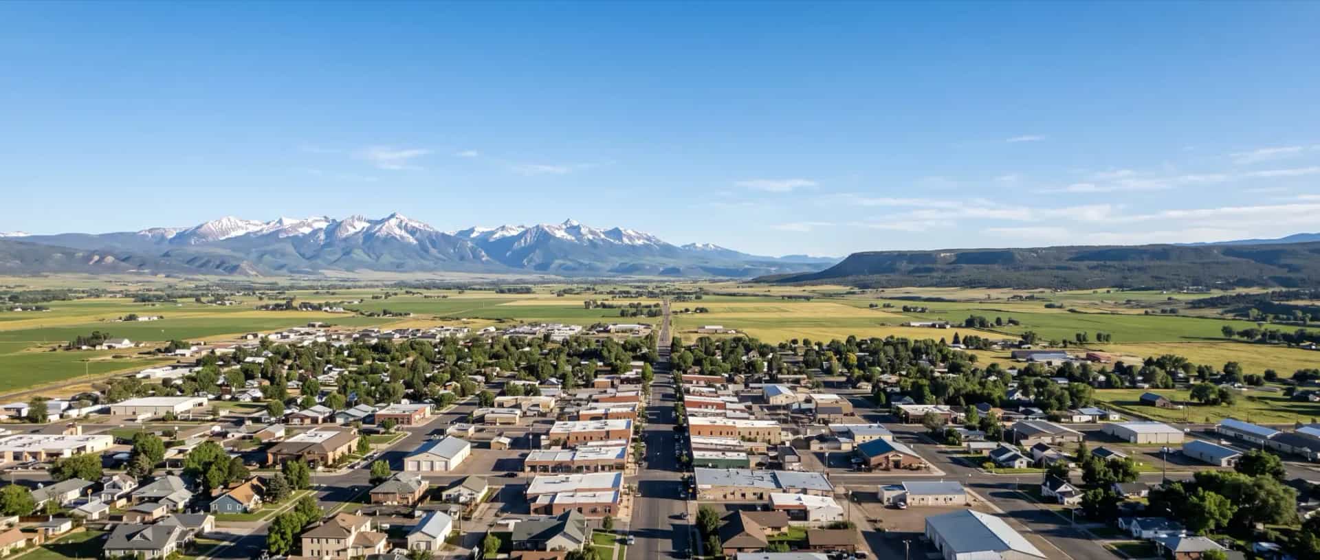 Illustrative representation of rooftops on the broad Uncompahgre Valley floor at Montrose, Colorado with the San Juan Mountains beyond