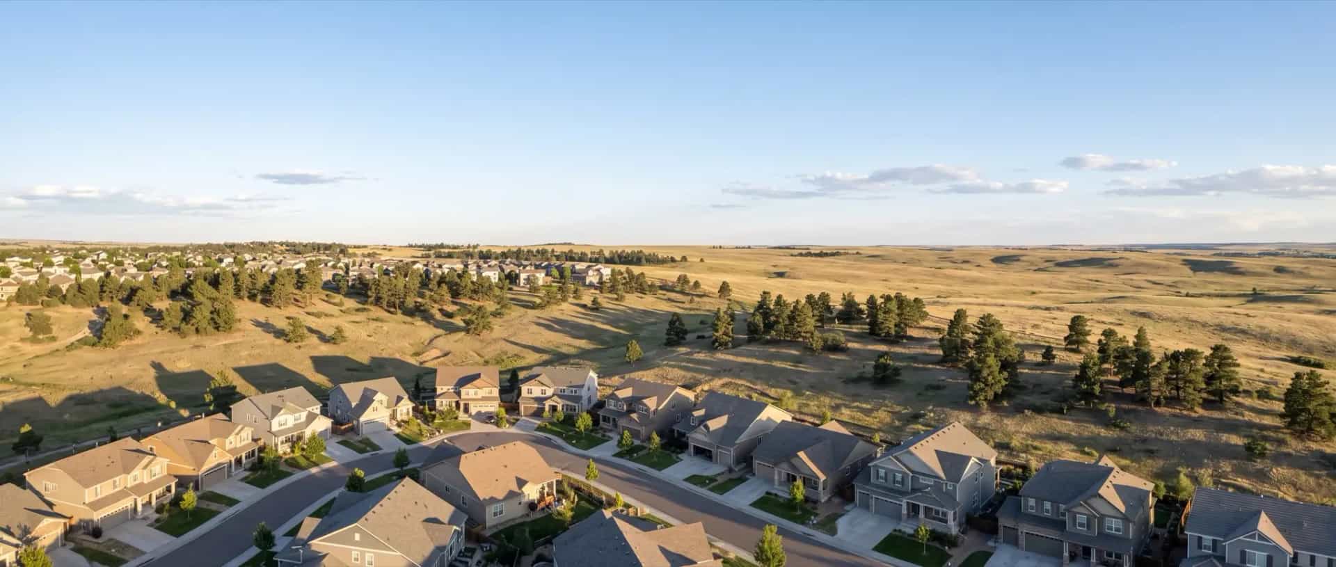 Illustrative representation of newer rooftops on rolling high prairie with scattered pines near Parker, Colorado