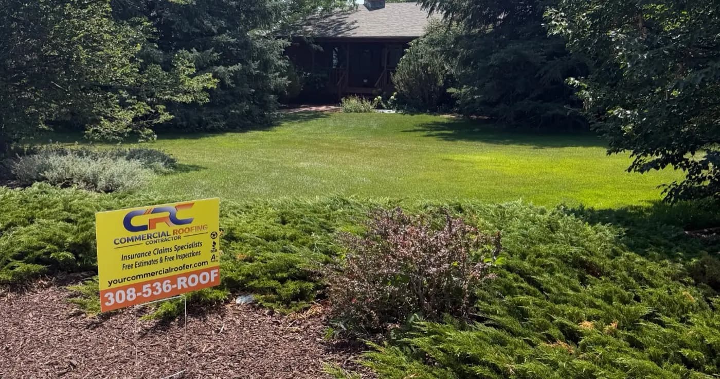 A Commercial Roofing Contractor yard sign in front of a Scottsbluff, Nebraska home with a completed shingle roof behind it
