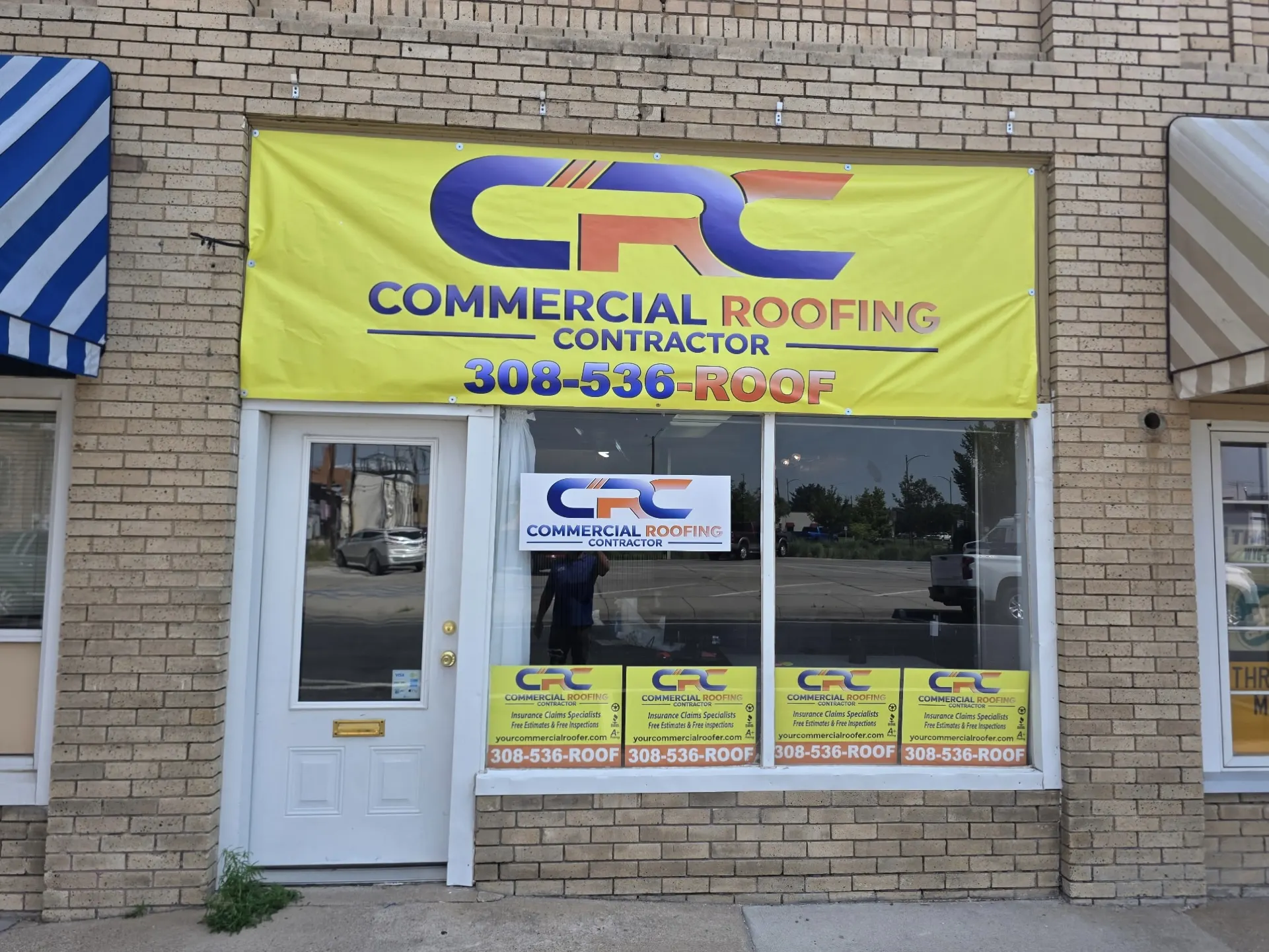 The Commercial Roofing Contractor office storefront in downtown Scottsbluff, Nebraska, with CRC signage and the 308-536-ROOF phone number in the window