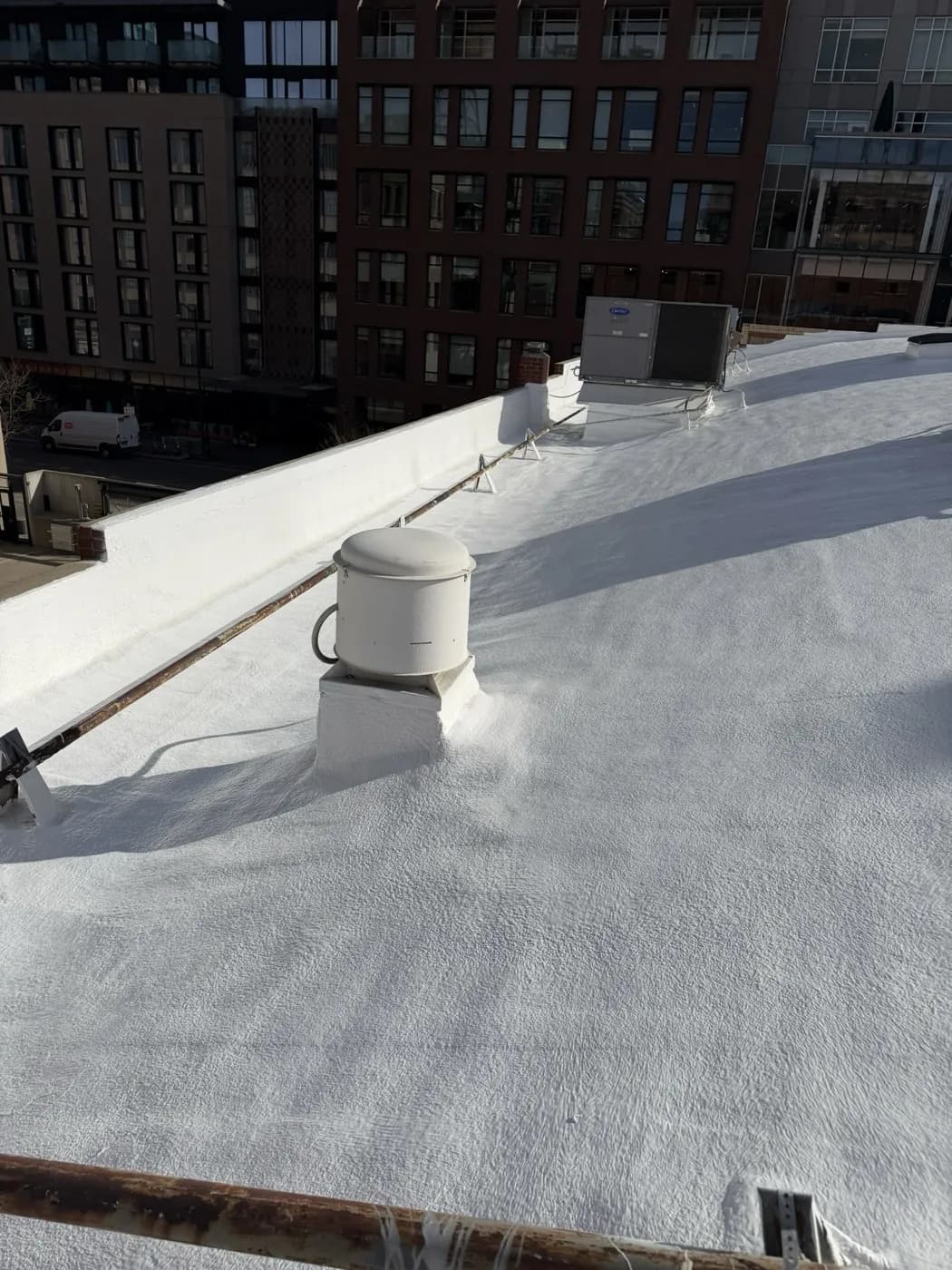 Detail of a white American WeatherStar Ure-A-Sil coating sealing a roof vent curb and parapet on a downtown Denver commercial building