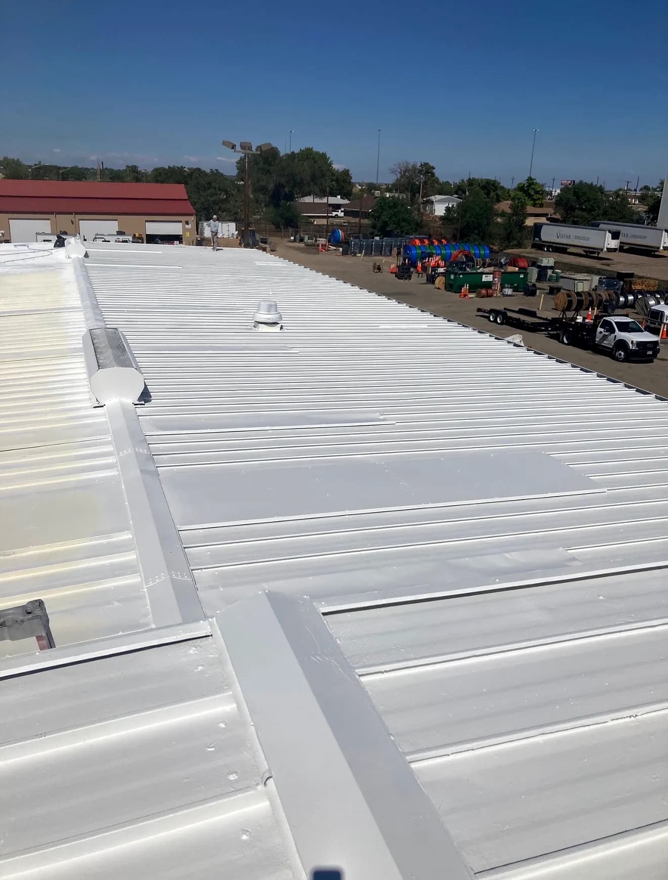 Detail of a completed white American WeatherStar coated metal roof with sealed seams on a Denver commercial building