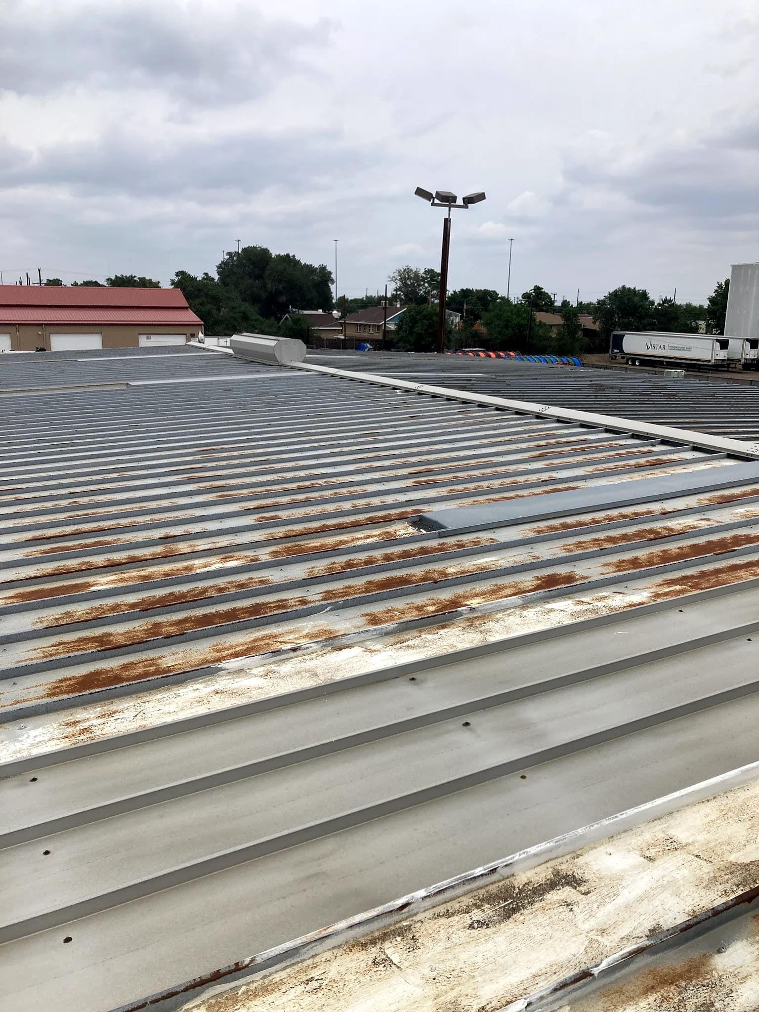 Heavily rust-streaked galvanized metal roof on a commercial building in Denver, Colorado before an American WeatherStar coating restoration