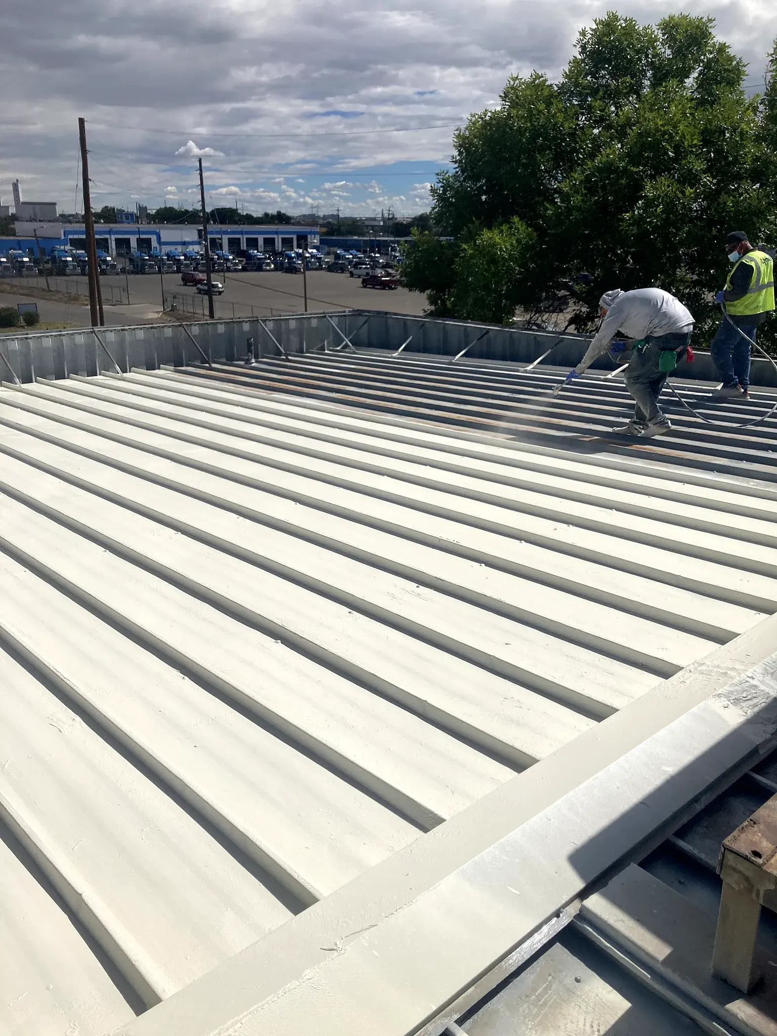 CRC crew spray-applying an American WeatherStar coating across a commercial metal roof in Denver, Colorado