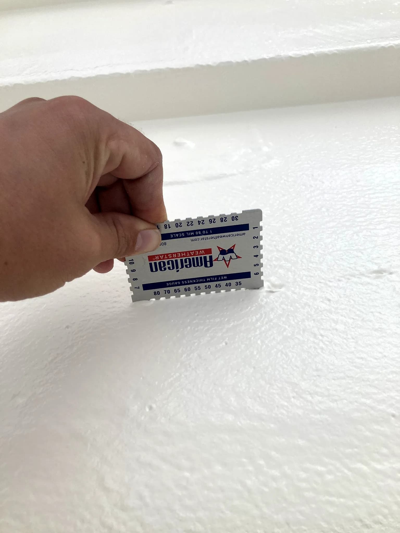 American WeatherStar wet-film thickness gauge checked on a freshly applied white roof coating in Denver, Colorado