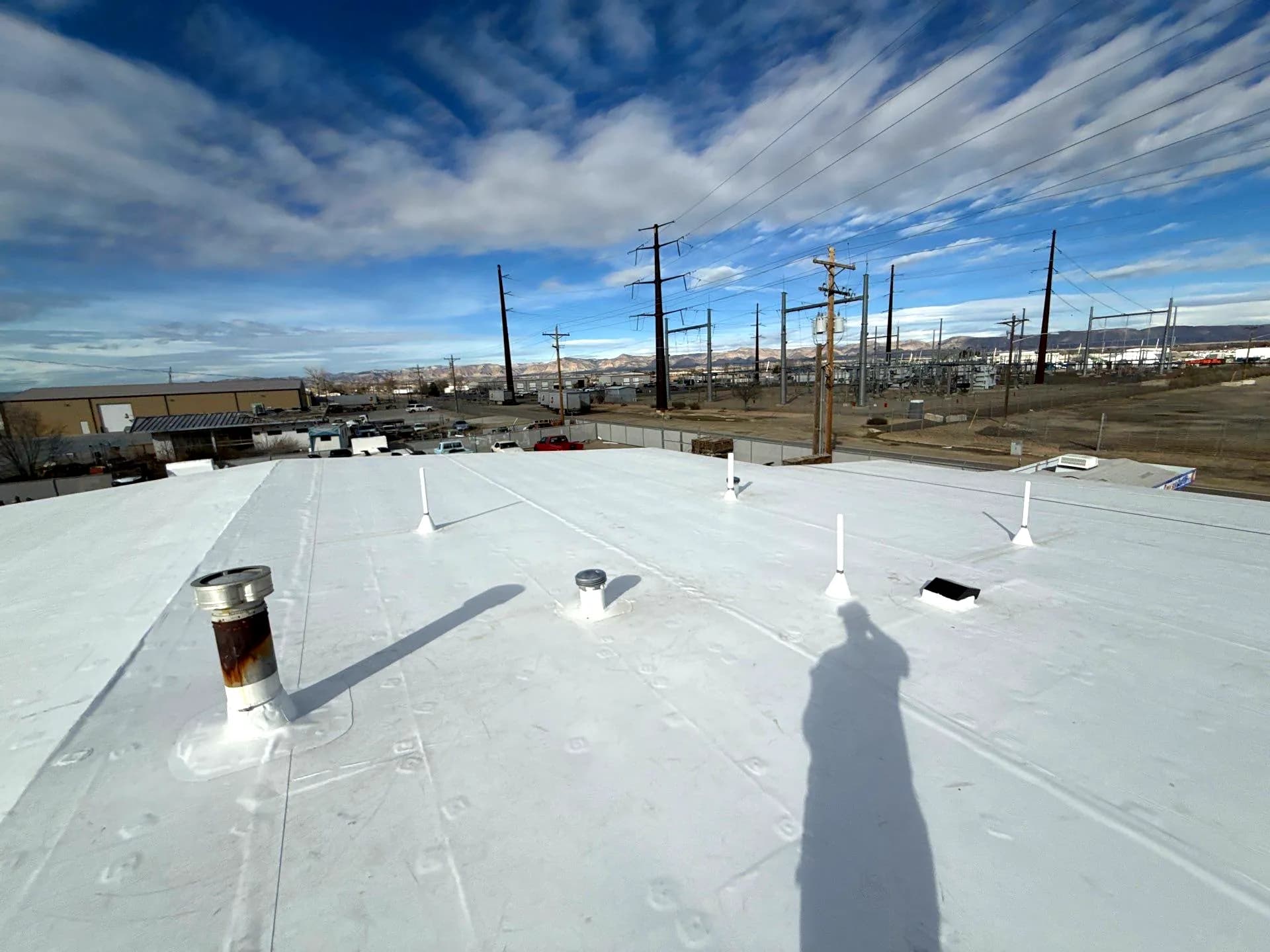 Finished seamless white TPO membrane roof with new pipe boot flashings on a commercial building in Grand Junction
