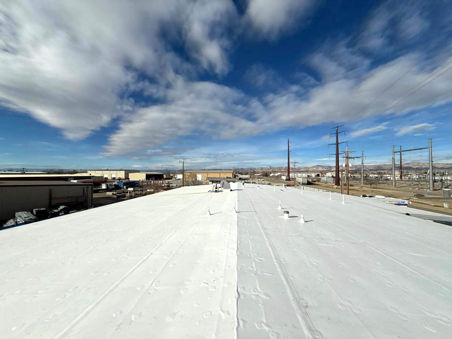 Aerial view of a completed white TPO membrane recover roof on a multi-tenant commercial building in Grand Junction, Colorado