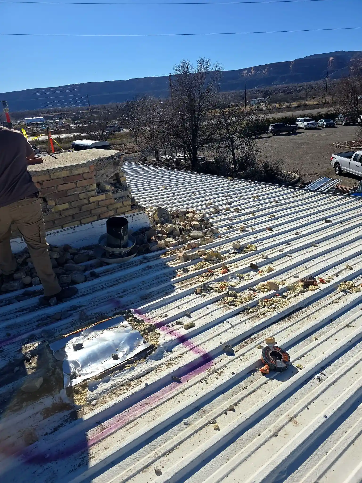 Aged ribbed metal roof on a Grand Junction commercial building with leak areas marked before a membrane recover