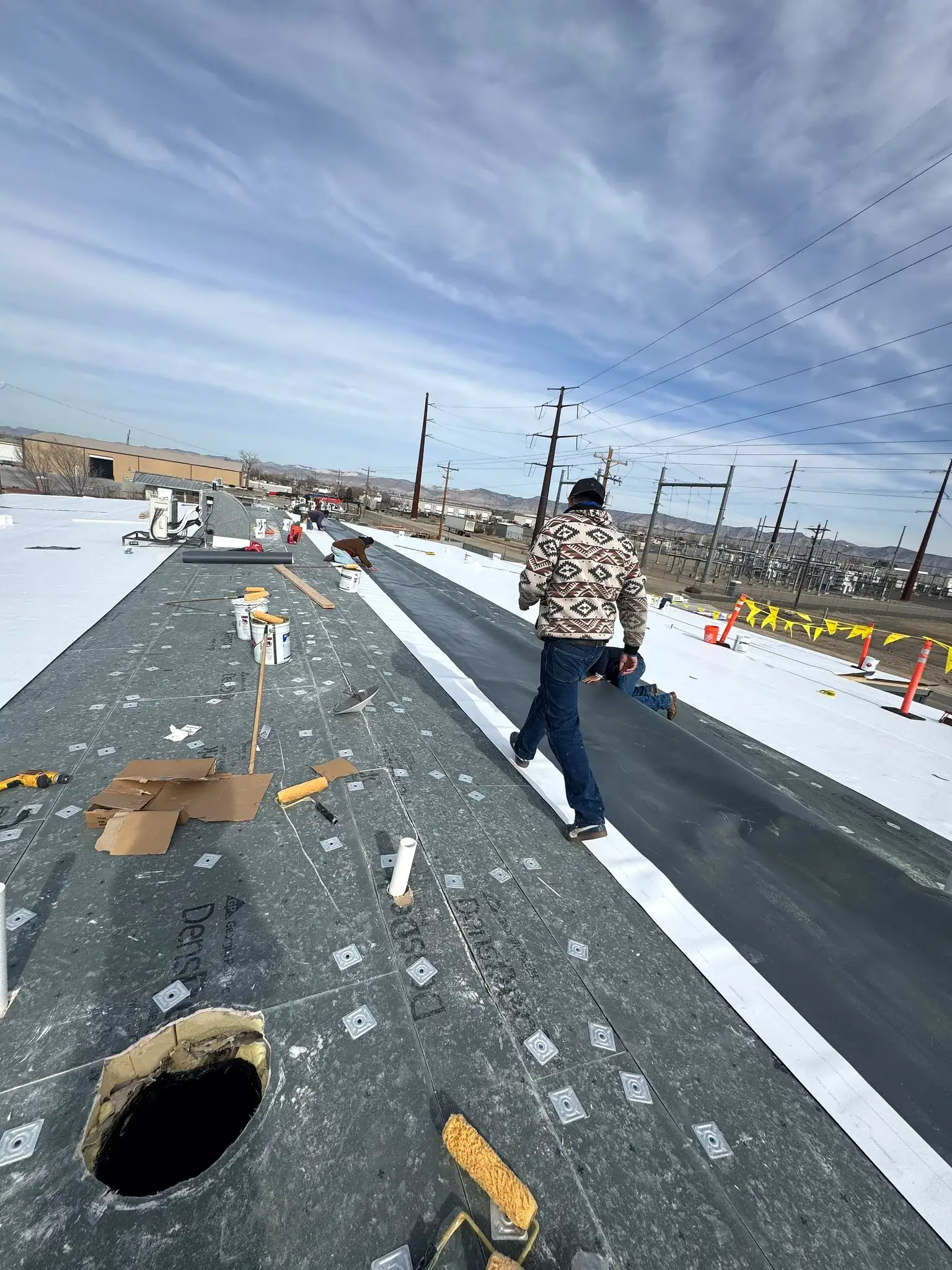 Johns Manville TPO membrane being adhered over a coverboard during a commercial roof recover in Grand Junction, Colorado