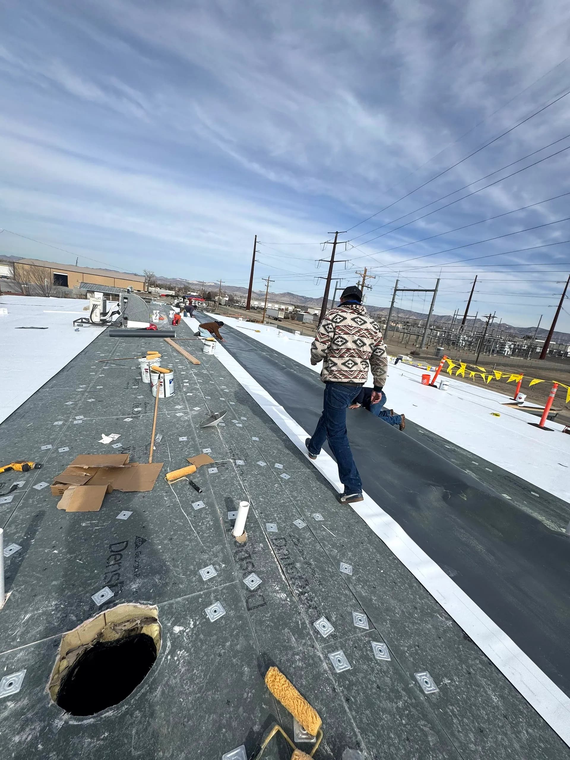 Johns Manville TPO membrane being adhered over a coverboard during a commercial roof recover in Grand Junction, Colorado