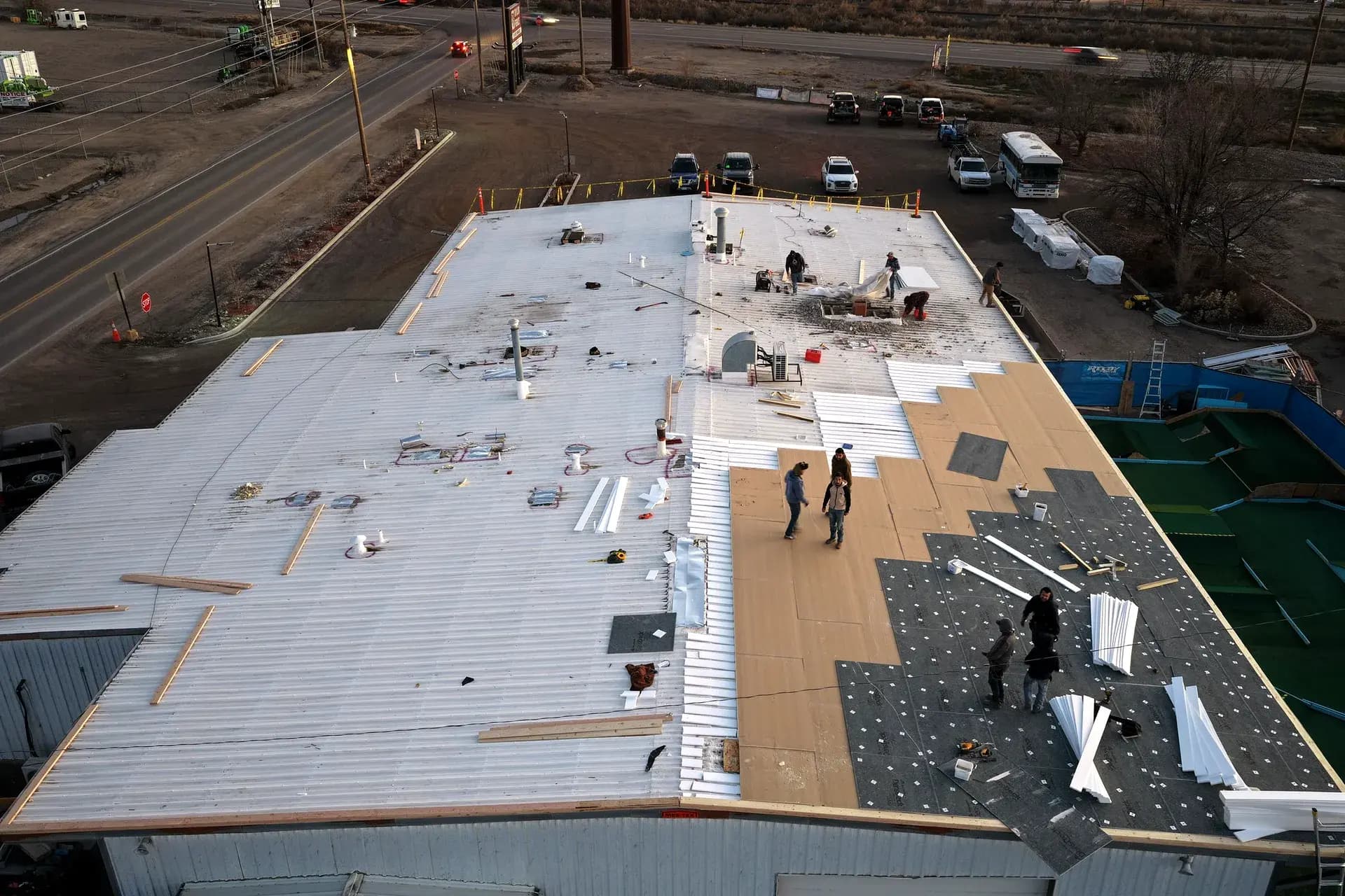 Dusk view of a commercial roof recover in Grand Junction showing the metal roof, insulation, and new TPO membrane in one frame