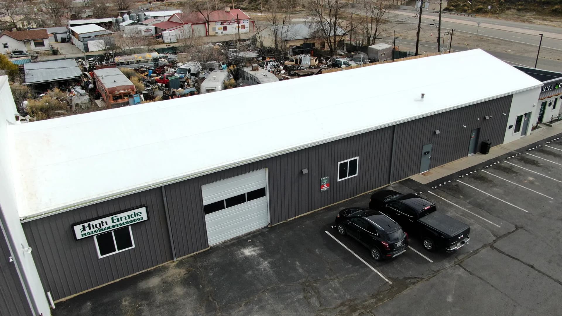 Aerial view of the completed white TPO membrane recover roof on the High Grade Concrete & Excavation building along Highway 50 in Grand Junction, Colorado