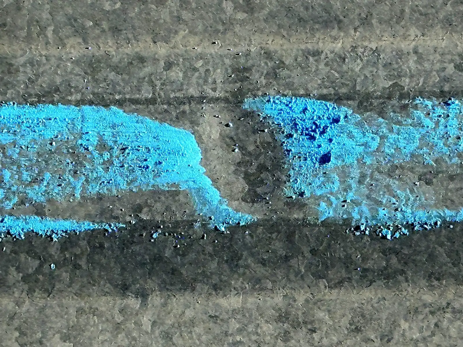 Close-up of a weathered galvanized metal roof panel with hail bruises circled in blue chalk on a commercial building in Grand Junction, Colorado