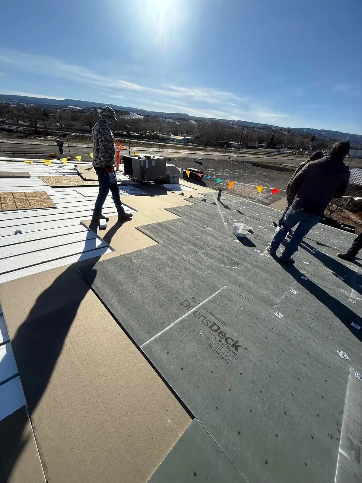 Crew installing Georgia-Pacific DensDeck Prime Roof Board with EONIC Technology over insulation on a commercial metal-roof recover in Grand Junction, Colorado