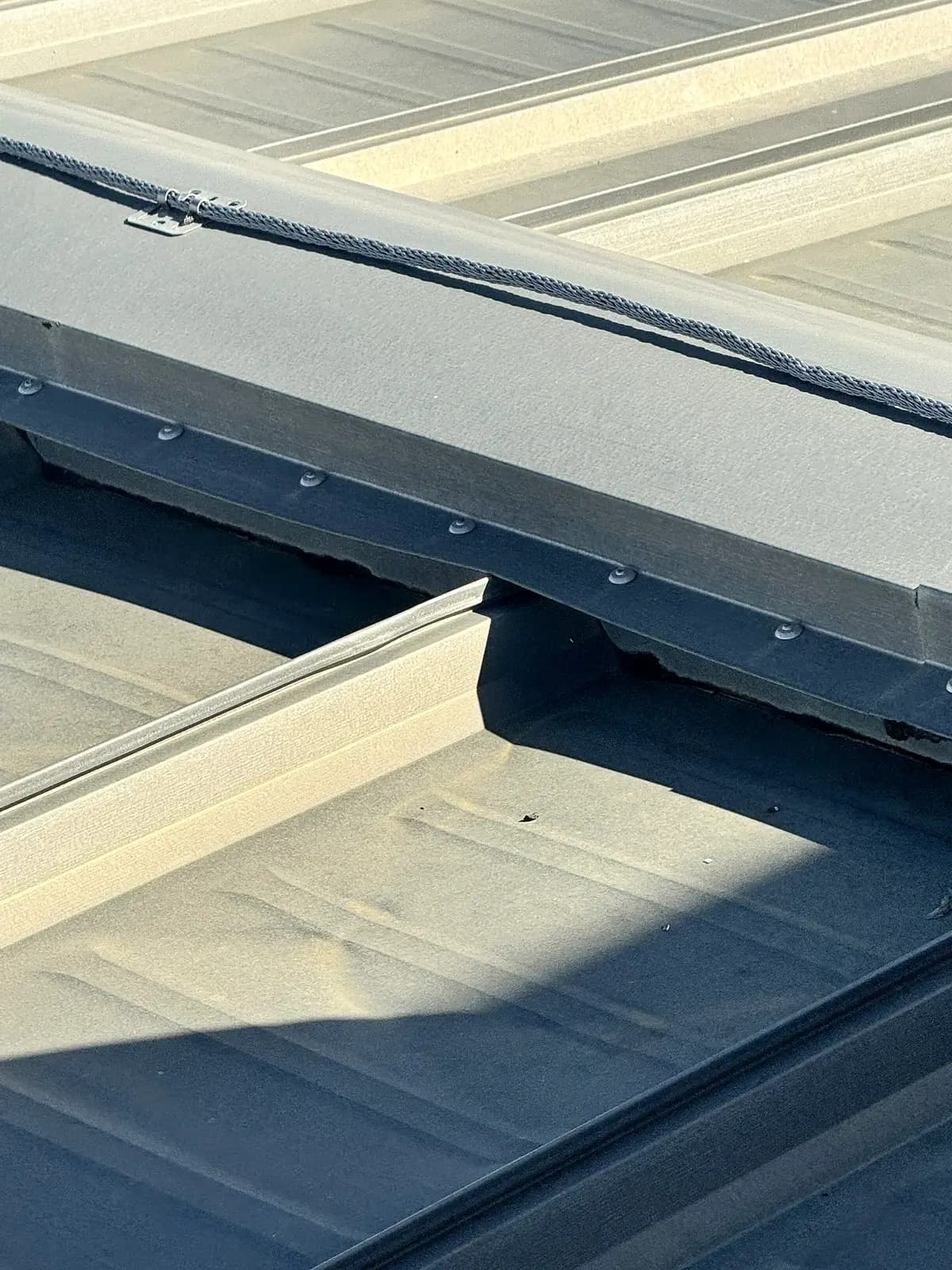 Ridge and curb flashing with exposed fasteners on a ribbed metal roof at an industrial facility in Denver, Colorado