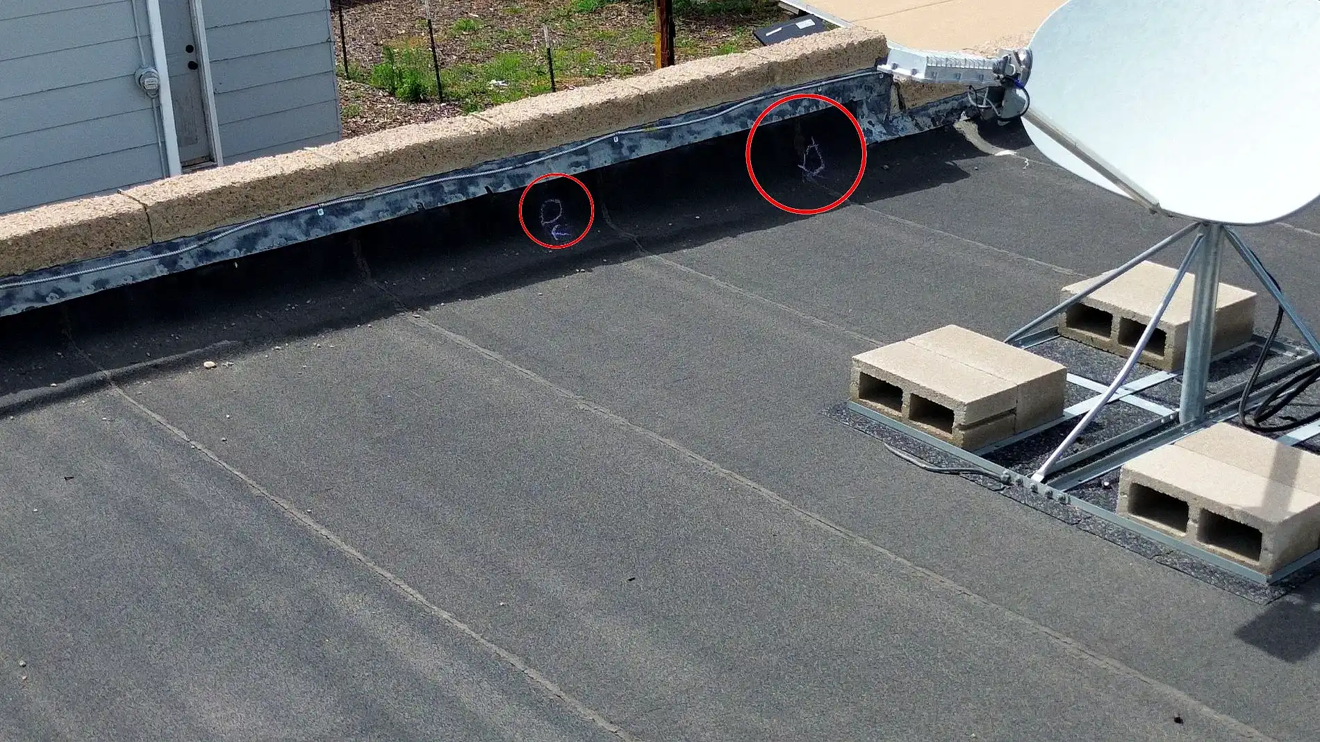 Hail impacts circled in red chalk on the low-slope roof of a commercial building in Greeley, Colorado