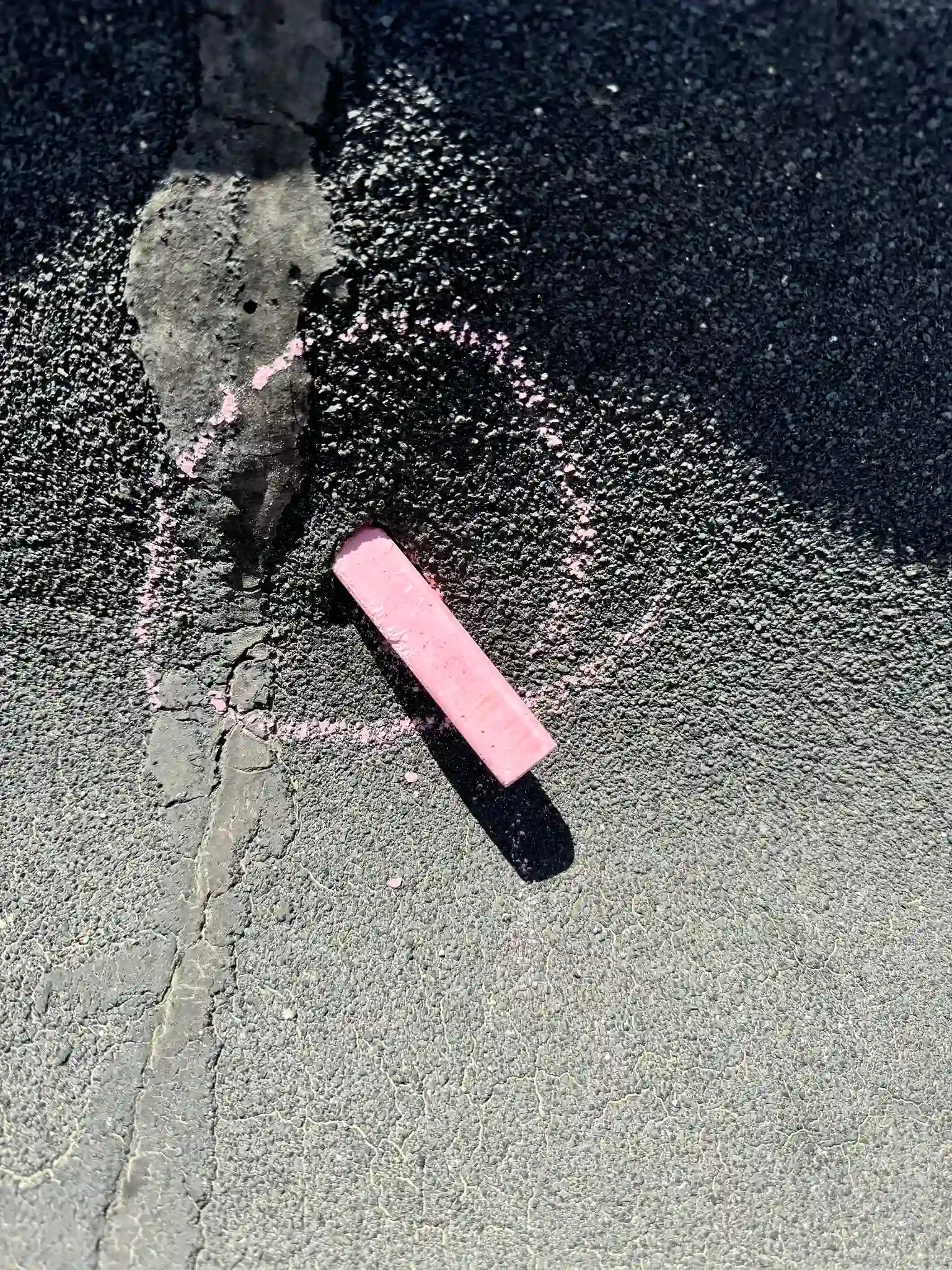 A stick of chalk marking a hail split along a seam on an aged low-slope roof membrane in Greeley, Colorado