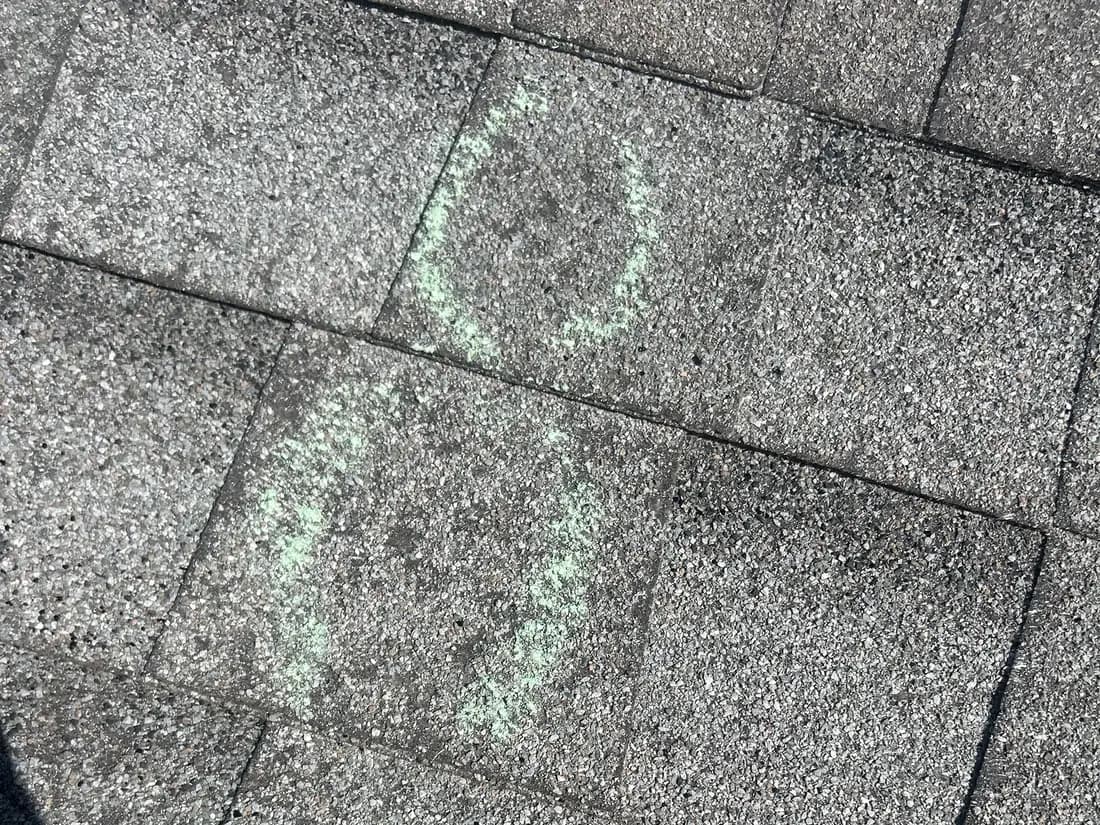 Close-up of asphalt shingles in Palisade, Colorado with individual hail impact marks circled in chalk