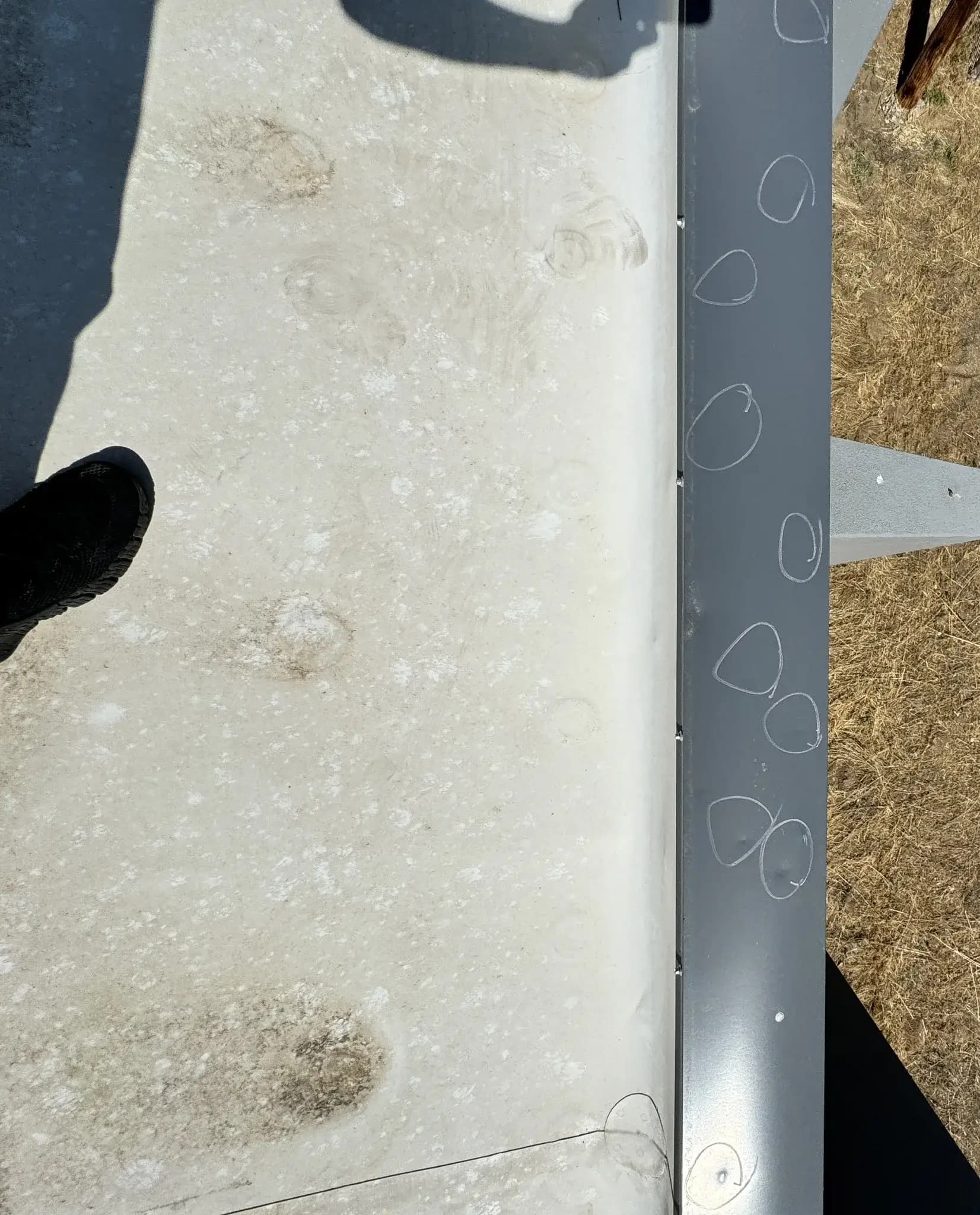 Hail-dented metal parapet cap circled in marker on a commercial roof in Denver, Colorado, documented for a hail claim