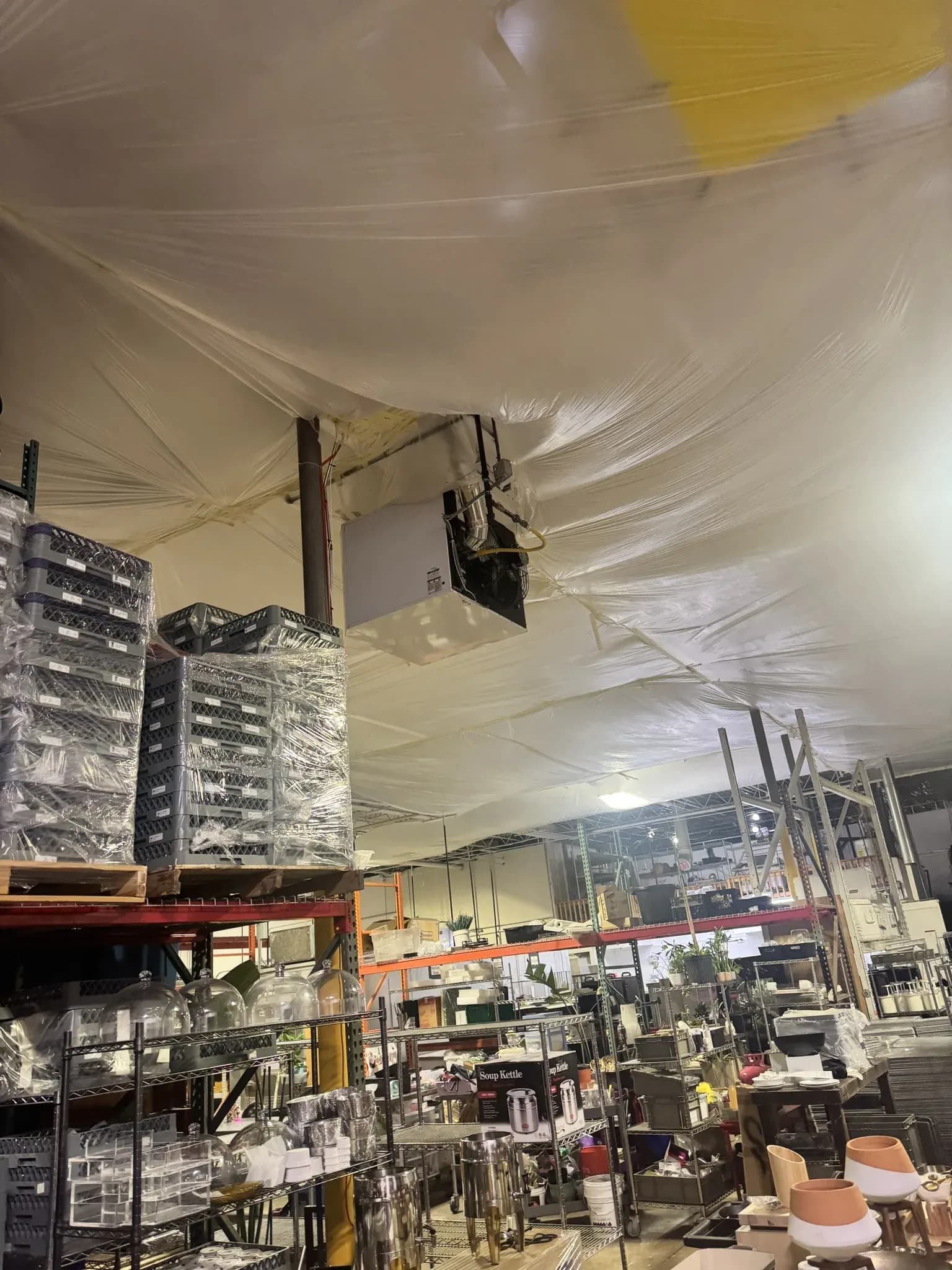 Interior plastic containment hung below the metal roof deck to protect a food-preparation warehouse during a roof replacement in Denver, Colorado
