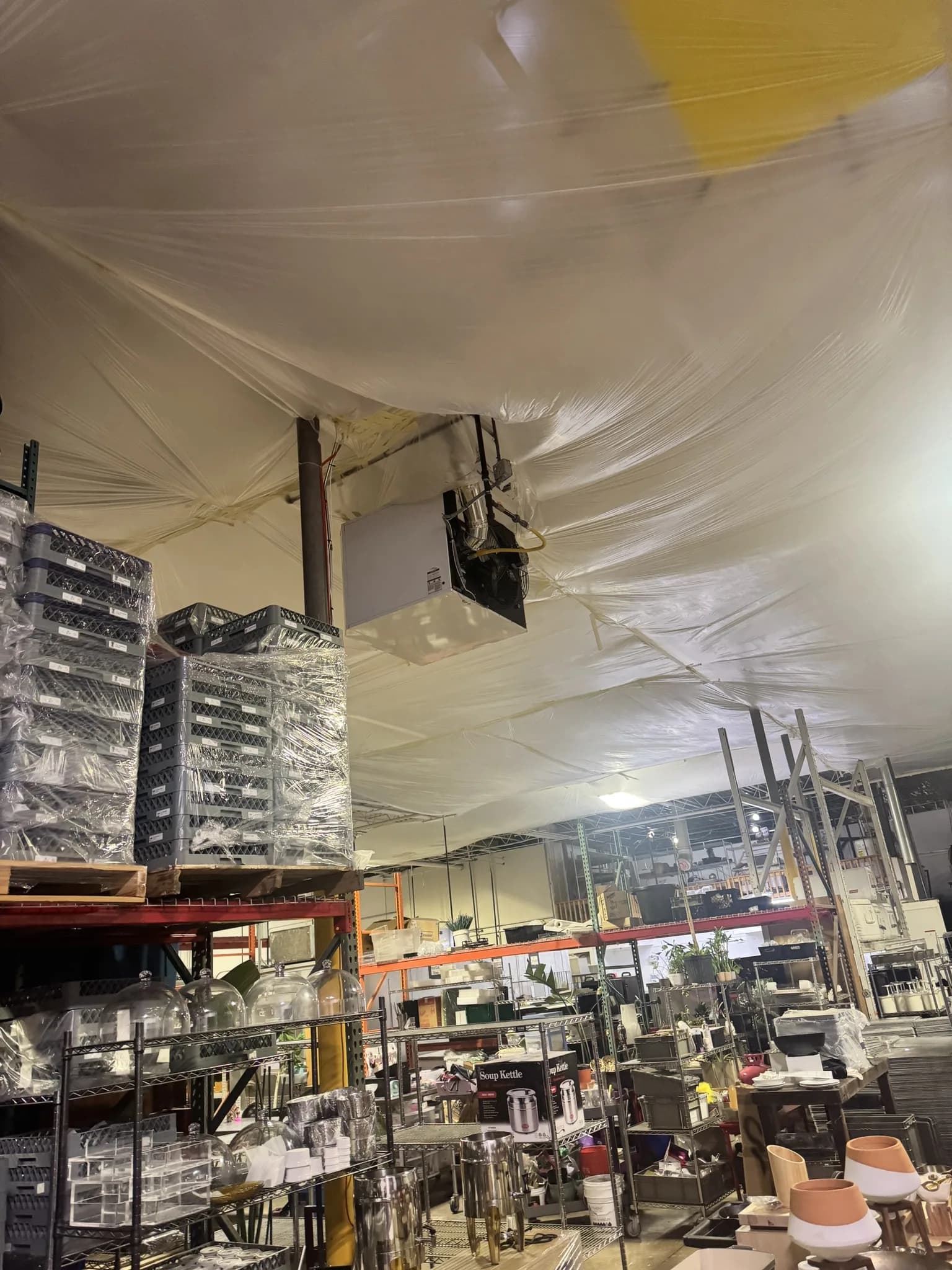 Interior plastic containment hung below the metal roof deck to protect a food-preparation warehouse during a roof replacement in Denver, Colorado