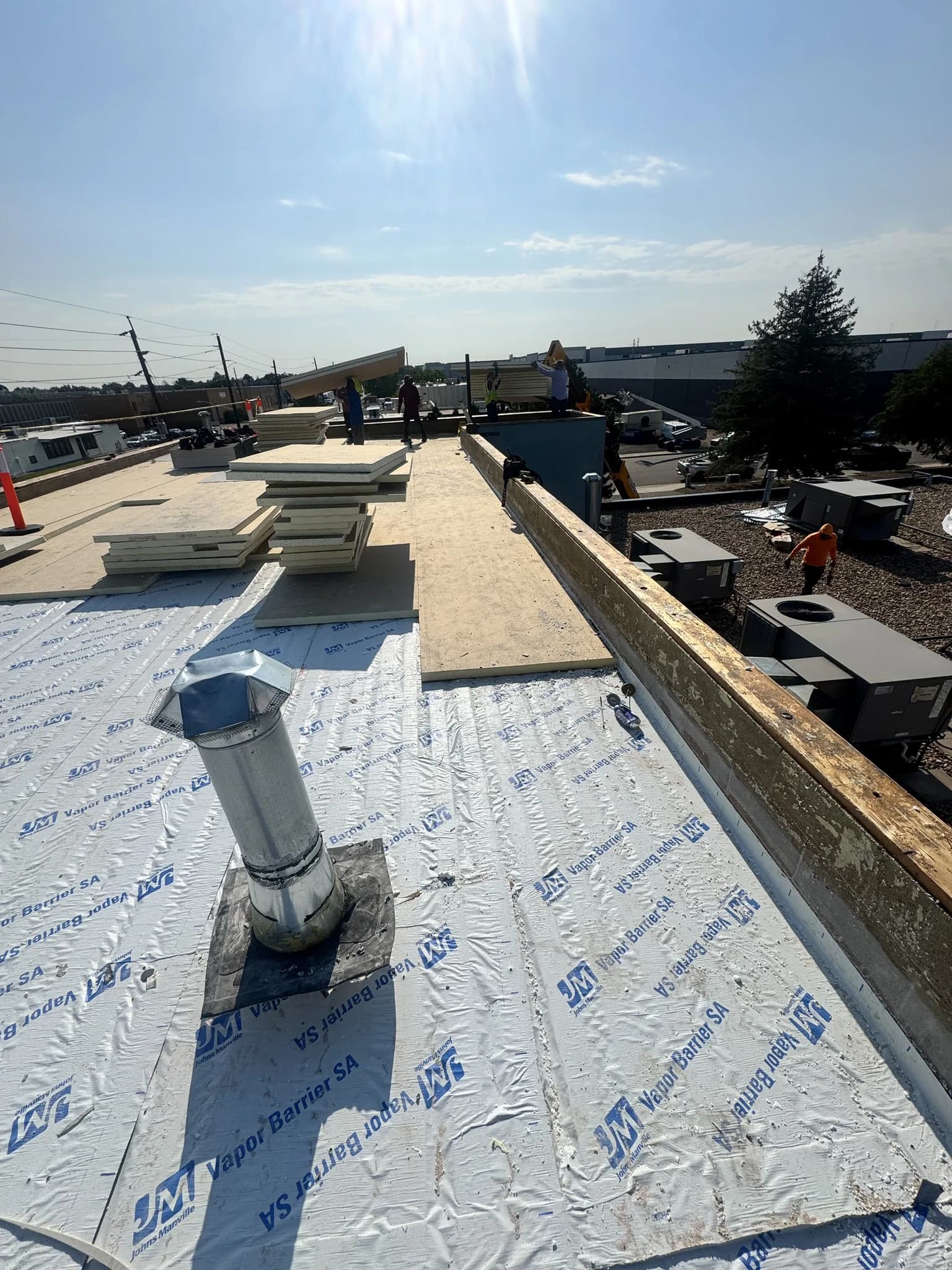 Johns Manville self-adhered vapor barrier and polyiso insulation boards staged during a commercial TPO roof rebuild in Denver, Colorado