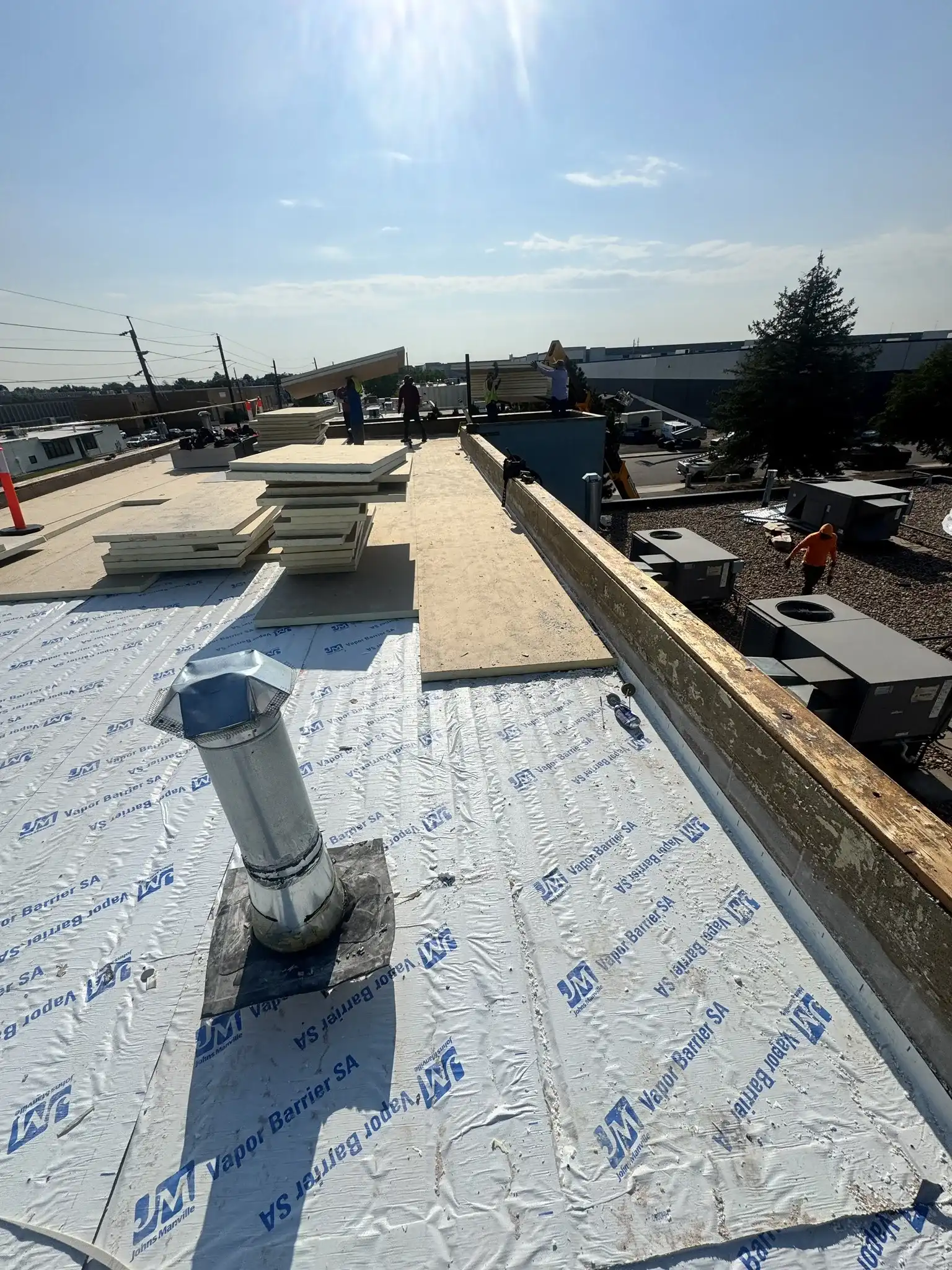 Johns Manville self-adhered vapor barrier and polyiso insulation boards staged during a commercial TPO roof rebuild in Denver, Colorado