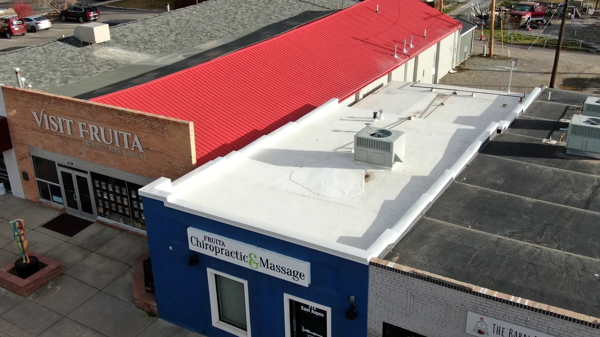 Aerial view of a completed white Johns Manville TPO roof on a commercial building in downtown Fruita, Colorado