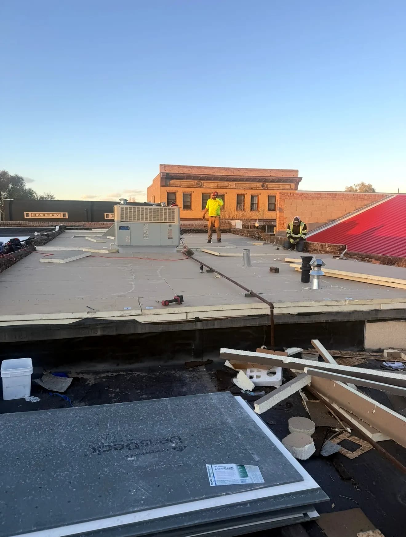 Tear-off in progress with new polyiso insulation and a Johns Manville cover board going down over the deck on a Fruita, Colorado commercial roof