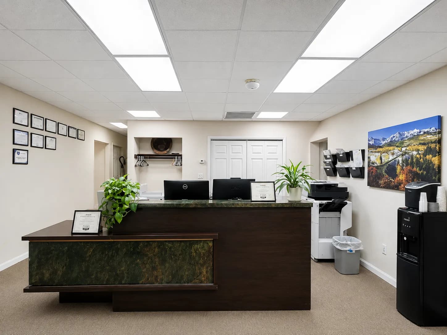 The reception area of the Commercial Roofing Contractor Denver office, with a green marble front desk, framed certifications on the wall, and a mountain landscape print