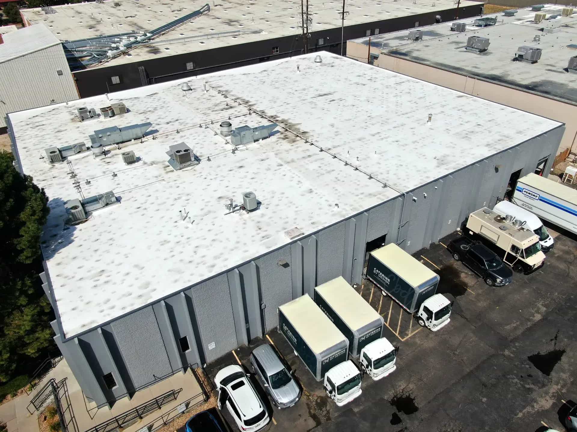 Aerial drone view of a completed commercial TPO roof replacement on an industrial warehouse in Denver, Colorado