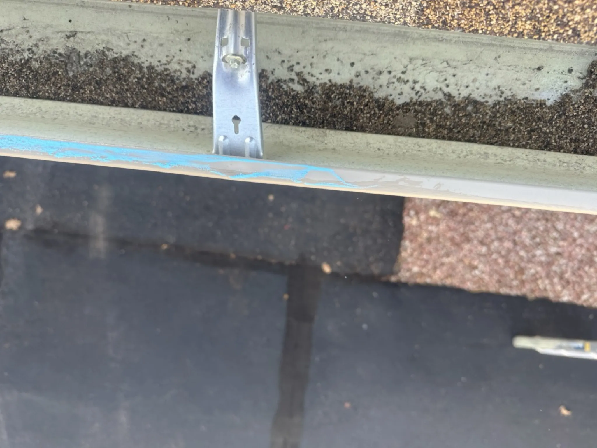 Hail damage to a metal gutter and drip edge on a Colorado Springs condominium, with dents and spatter marks revealed by chalk