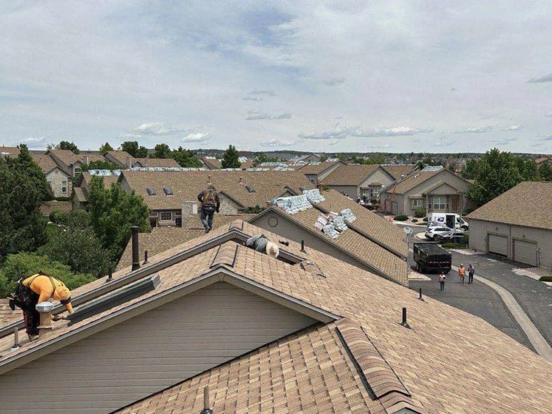 Aerial view of a Colorado Springs condominium community mid-reroof, with CRC crews on multiple buildings and new shingle bundles staged across the roofs