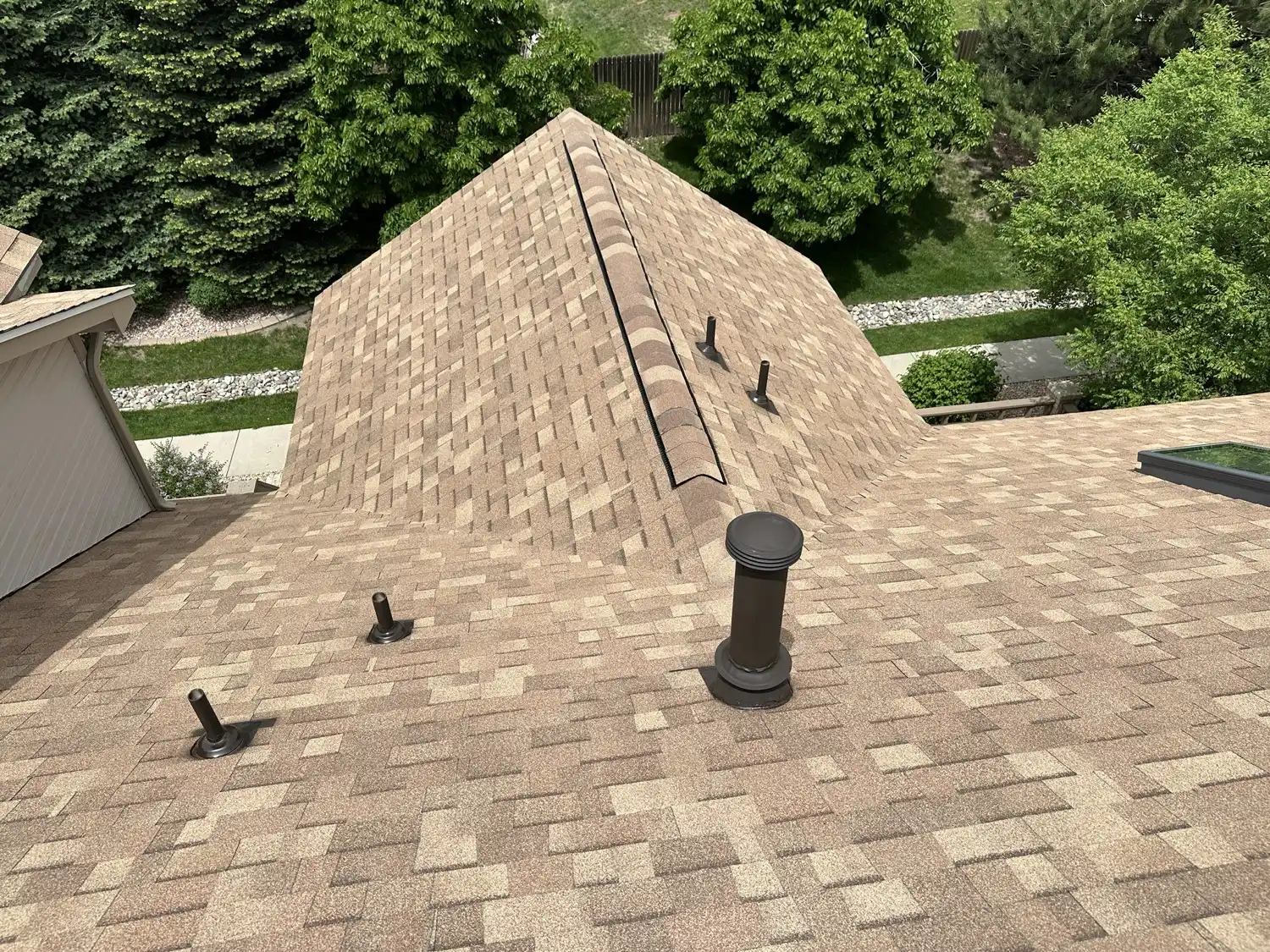 Close-up of a finished Malarkey architectural shingle hip roof on a Colorado Springs condominium, with a new ridge vent, new vent boots, and a replaced skylight