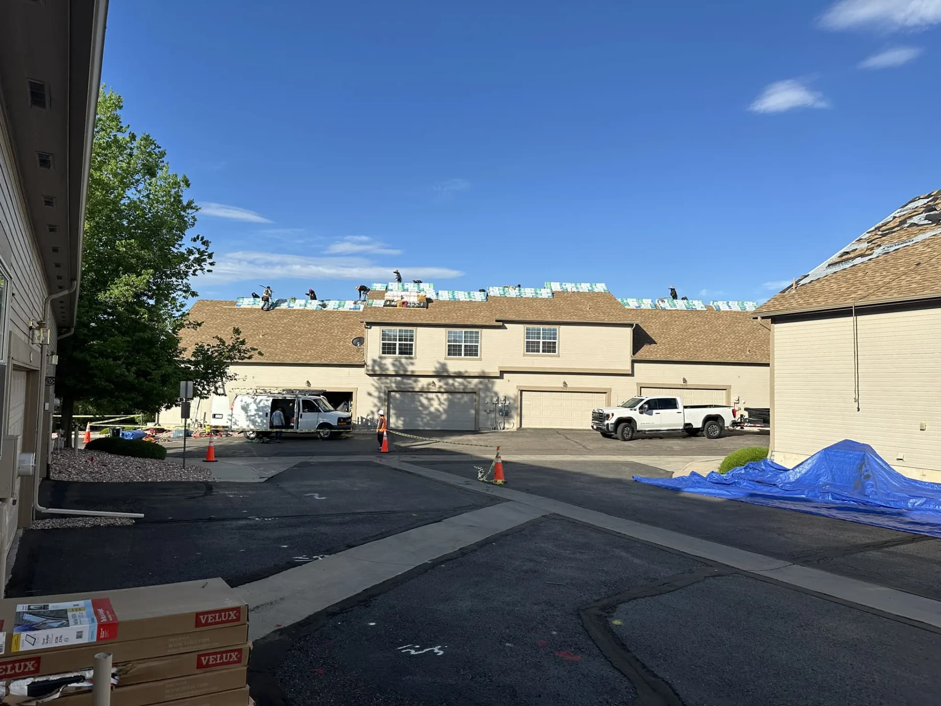 A Colorado Springs condominium roof mid-installation with new skylights set in and shingle bundles staged, a CRC crew member working nearby