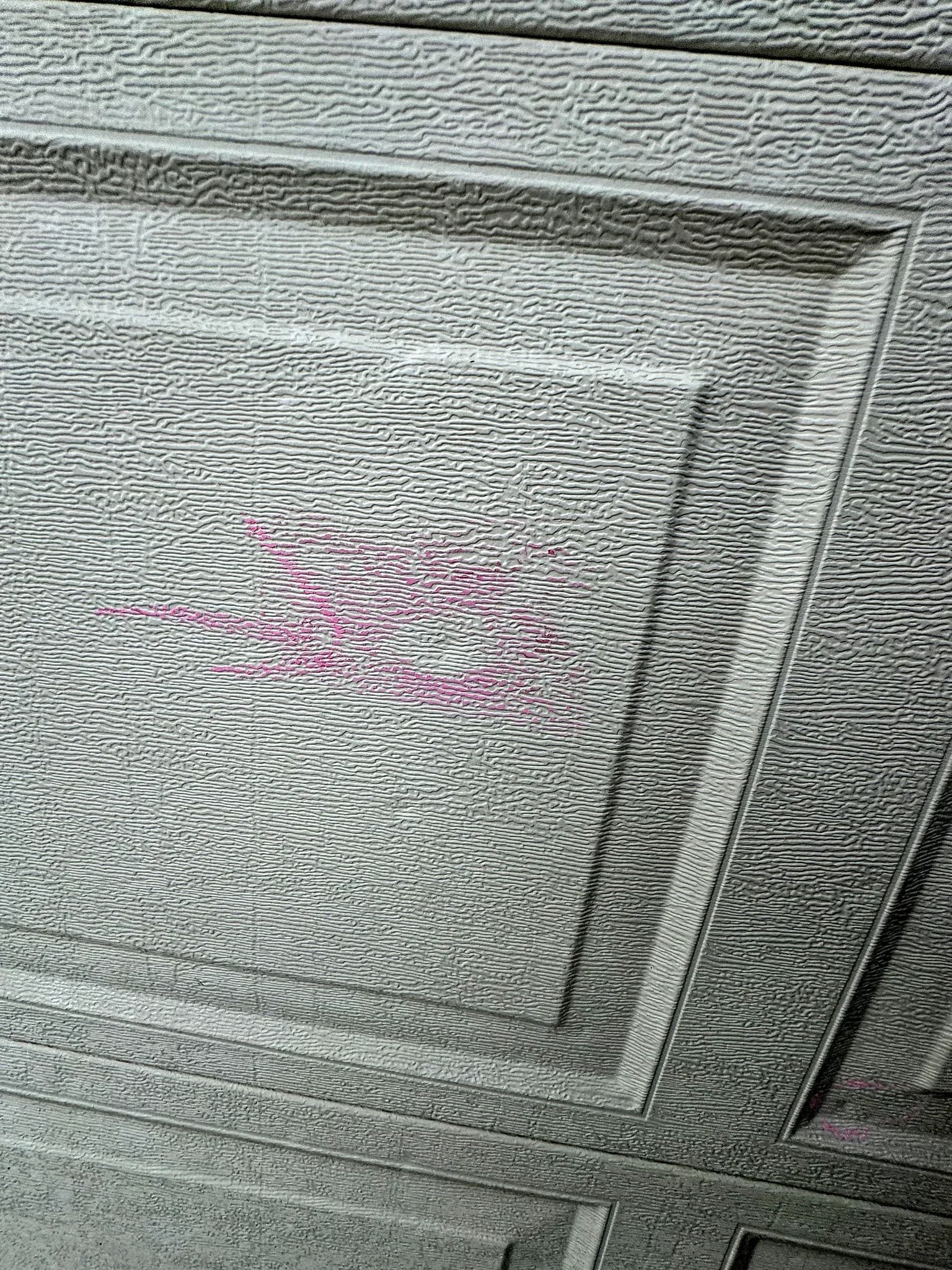 Hail dents across a metal garage door on a home in Colorado Springs, showing storm impact on soft metals