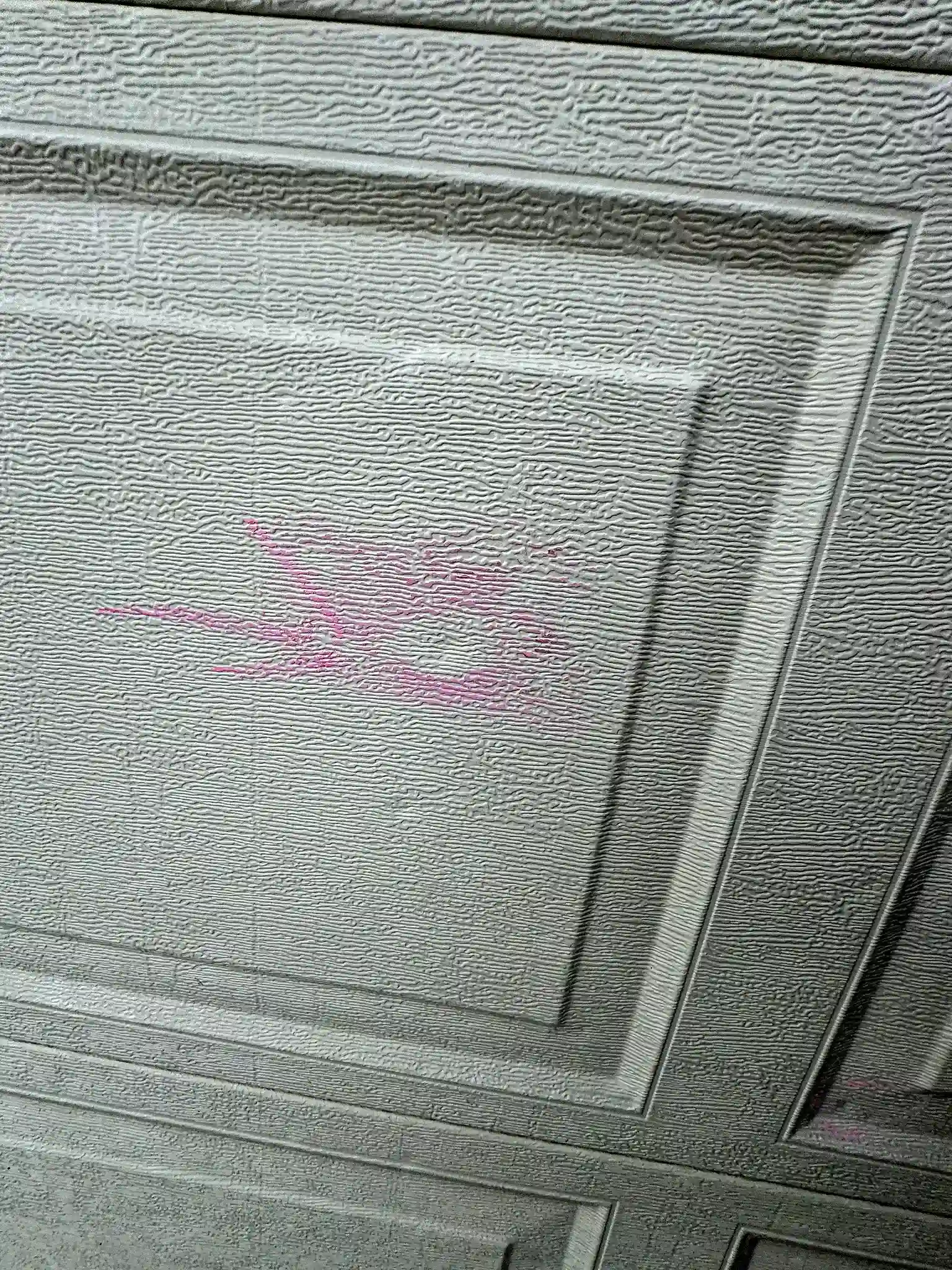 Hail dent circled on a steel garage door at a home in Colorado Springs, Colorado, documented for an insurance claim