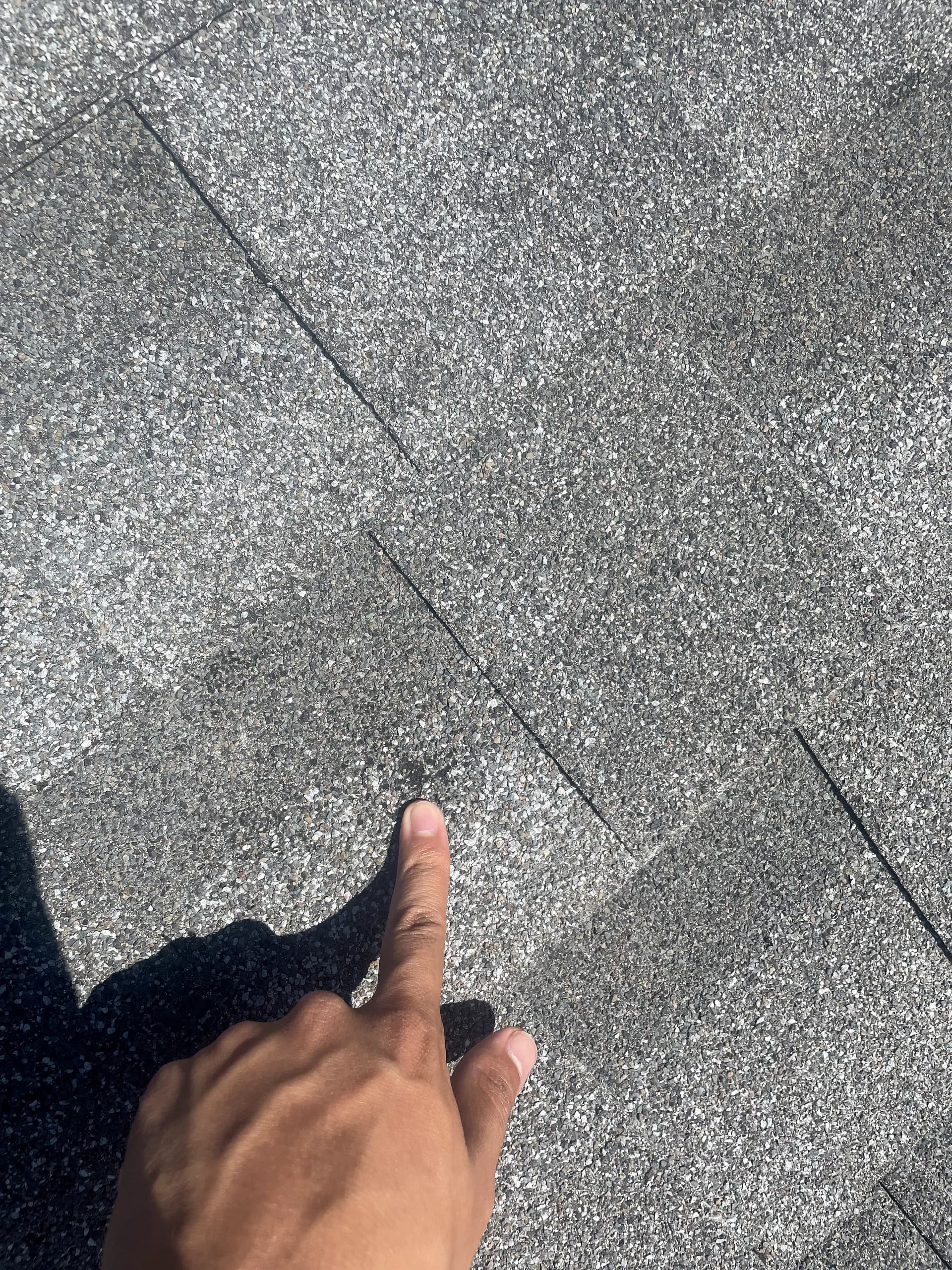 Roofer inspecting and documenting hail-damaged shingles on a residential roof in Aurora, Colorado