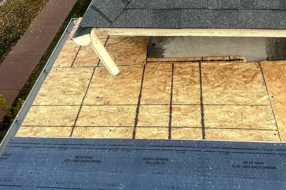 A roof slope on a Grand Junction, Colorado home stripped to new OSB decking with synthetic underlayment run along the eave, while the adjacent slope beside it still carries its old grey shingles