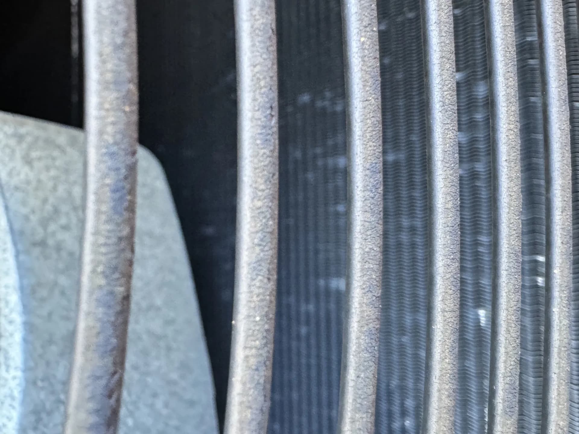 Close-up of an air conditioning condenser in Castle Pines, Colorado, with aluminum cooling fins bent and flattened by hail impacts