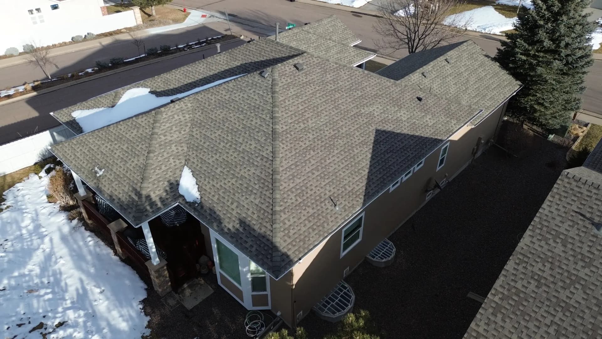 Aerial view of a completed GAF Timberline AS II Class 4 impact-resistant shingle roof on a single-family home in Castle Pines, Colorado, with a freshly re-stained deck below