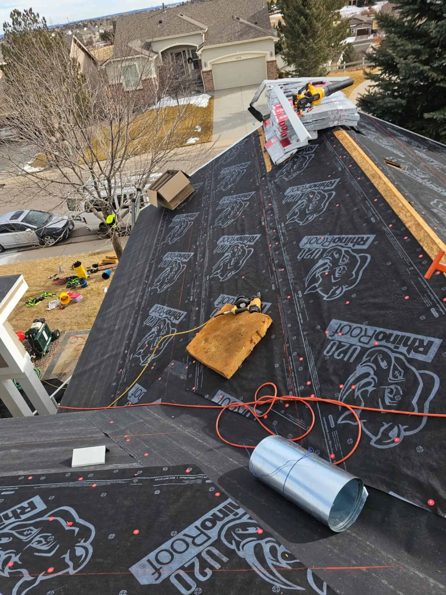 RhinoRoof synthetic underlayment installed across a Castle Pines, Colorado, roof with new shingle bundles staged along the ridge