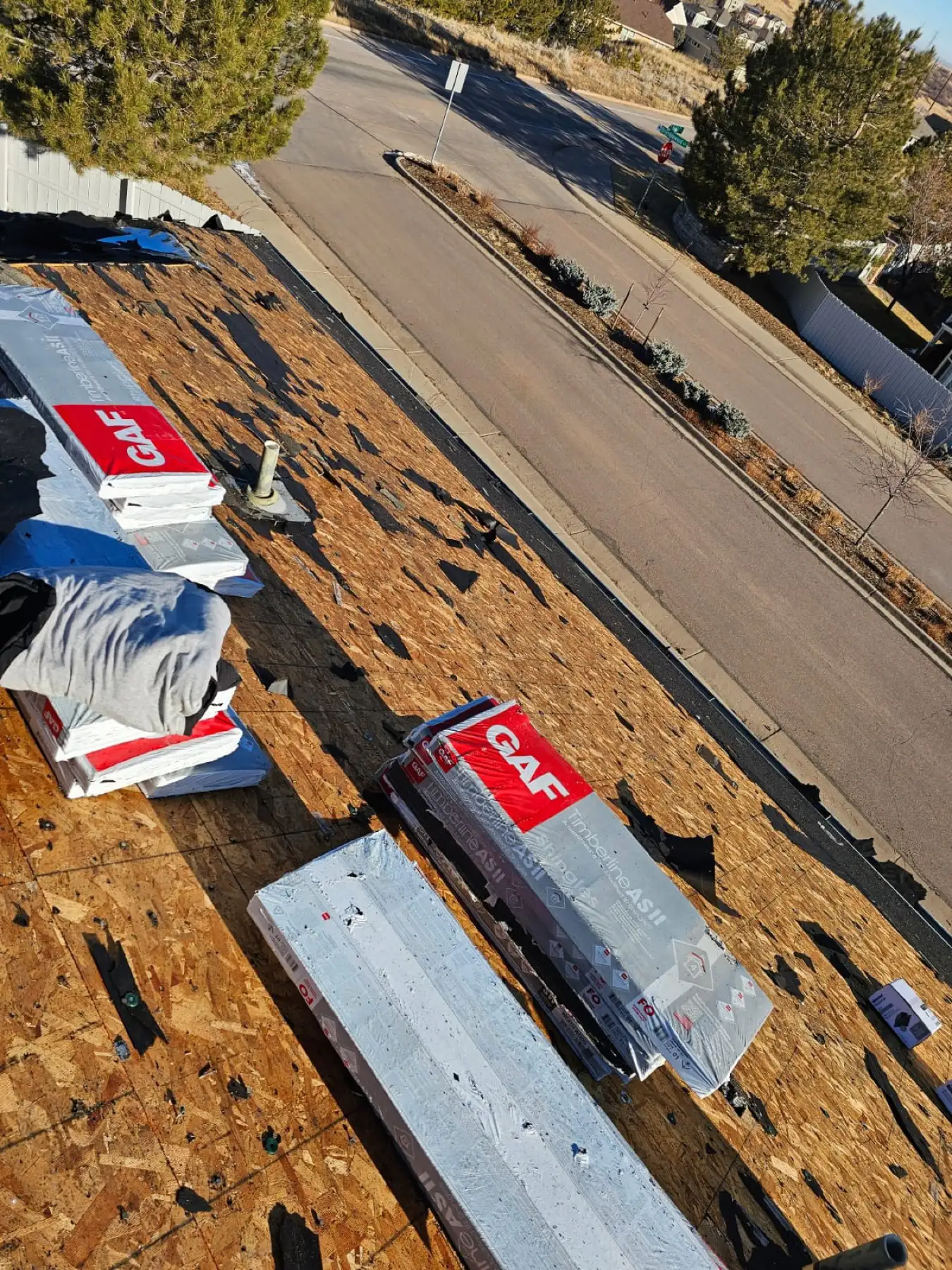 Roof torn off to bare wood decking on a Castle Pines, Colorado, home with GAF Timberline AS II Class 4 shingle bundles staged for installation