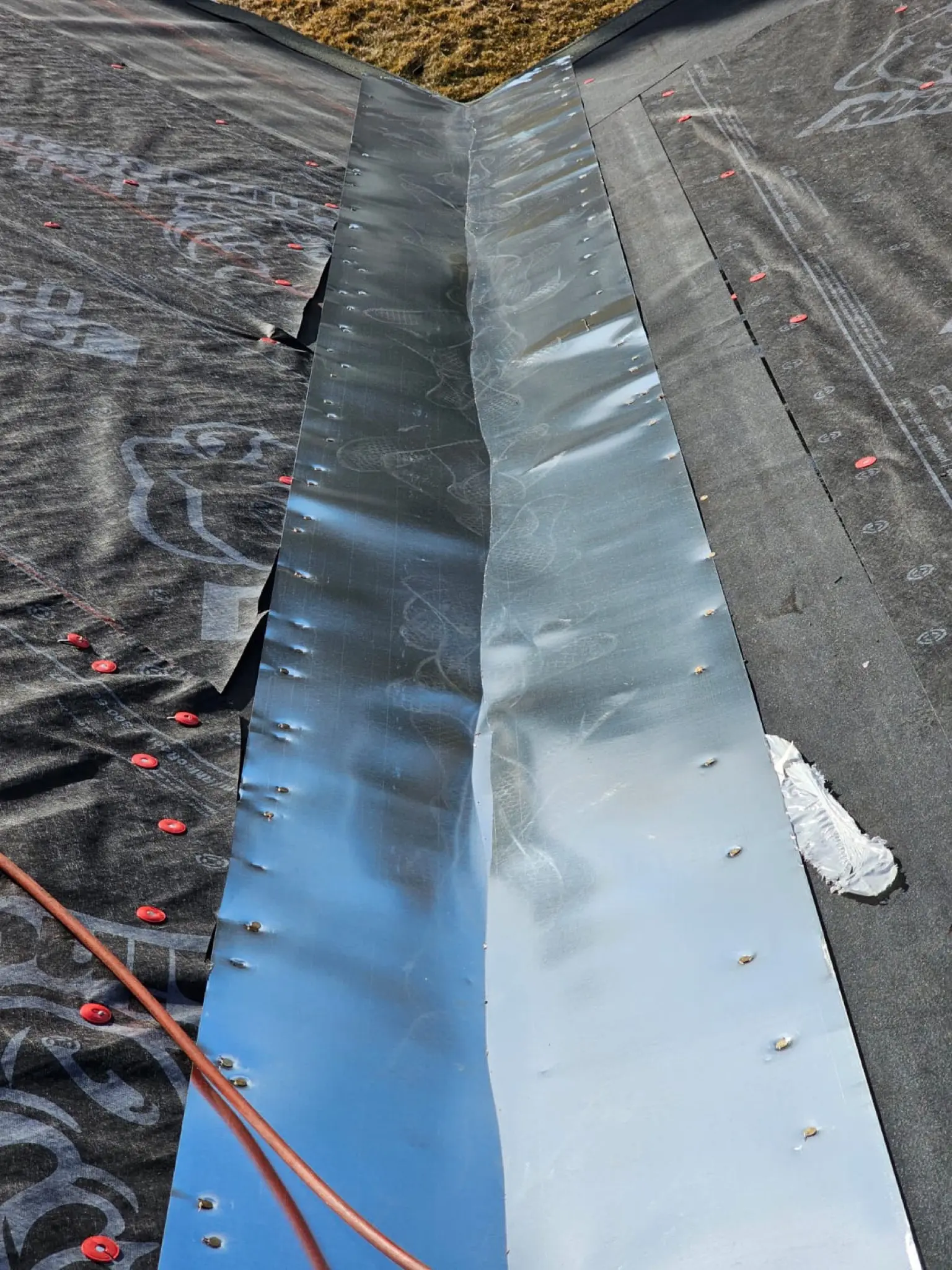 New metal valley flashing installed over synthetic underlayment on a Castle Pines, Colorado, roof during a shingle replacement