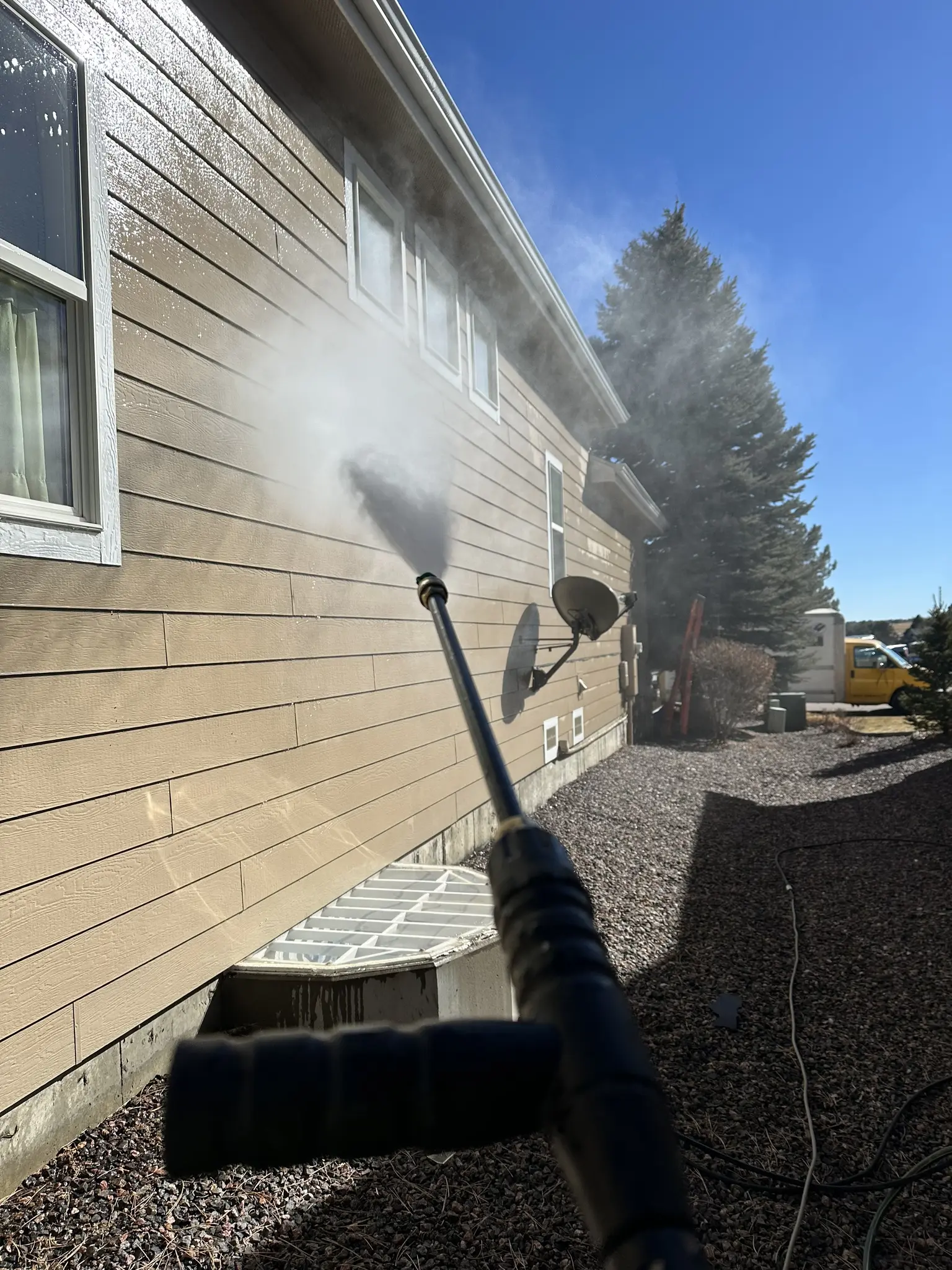 A CRC crew member pressure-washing the lap siding of a Castle Pines, Colorado, home to prep it for a storm-damage exterior repaint