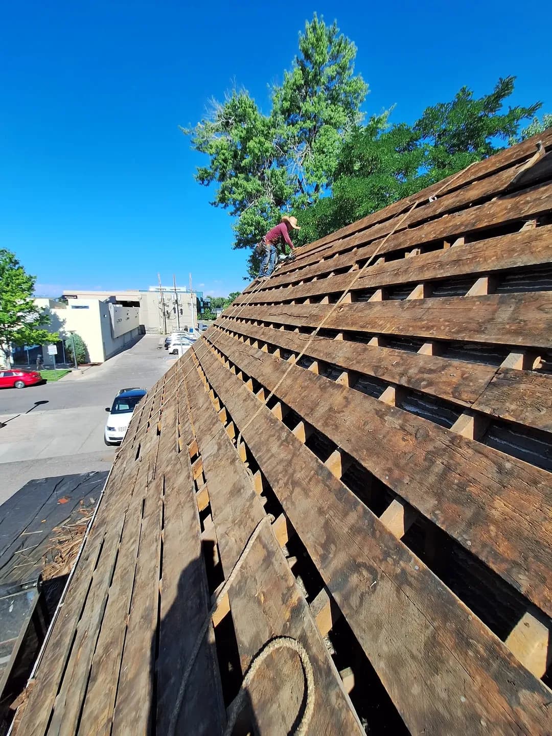 Bare spaced board decking with open gaps exposed across a steep roof in Denver, Colorado, after the original wood shakes were removed