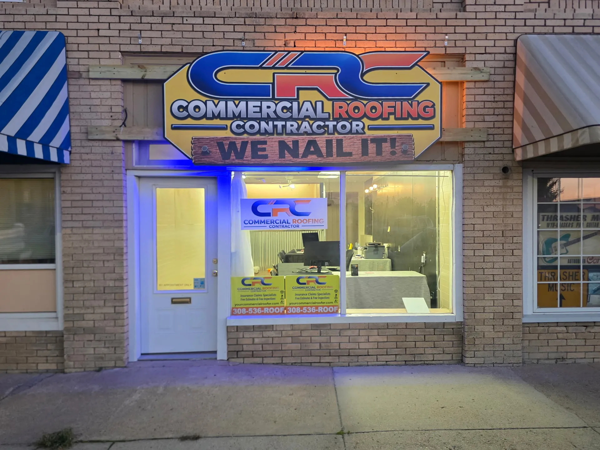 The Commercial Roofing Contractor Scottsbluff office, a tan brick storefront with a yellow CRC sign above the window and CRC signs in the glass