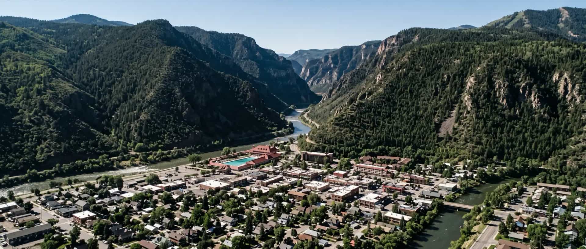 Illustrative representation of rooftops packed onto the narrow valley floor at Glenwood Springs, Colorado between steep canyon walls
