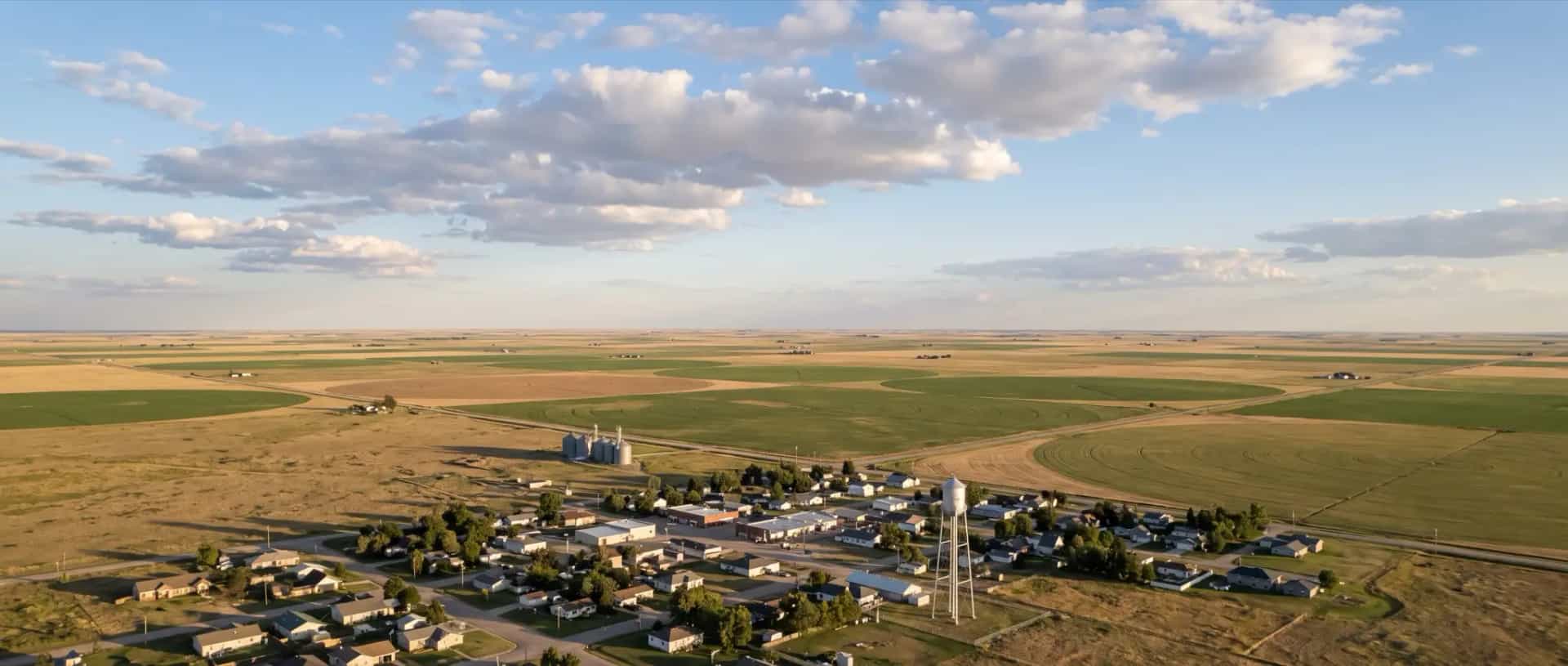 Illustrative representation of a small village surrounded by open farmland and rangeland at Minatare, Nebraska under a wide plains sky